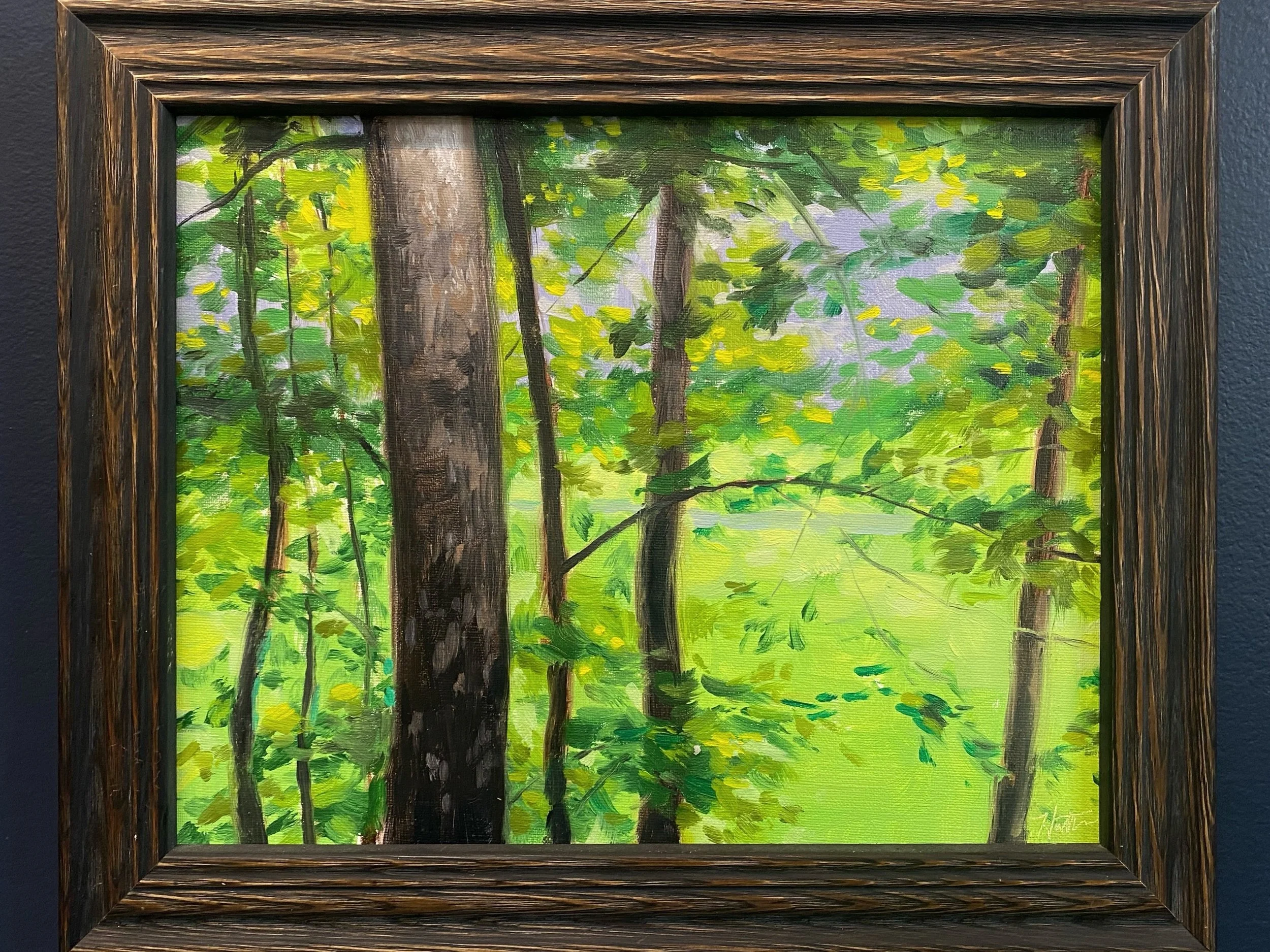 A framed painting of a lush green forest with trees and foliage, painted in an impressionistic style.
