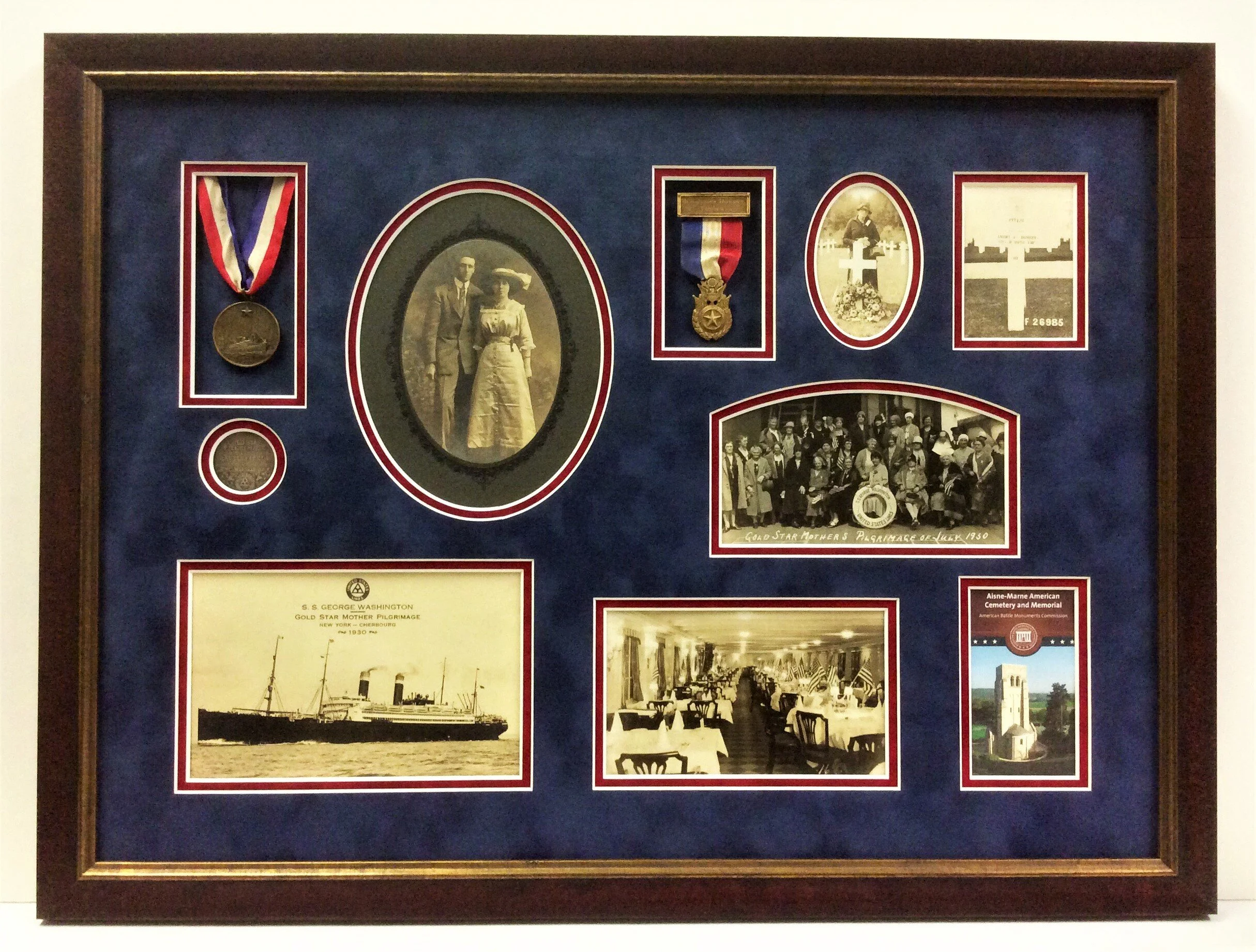 Display case with vintage photographs, medals, and memorabilia, framed in dark wood, dedicated to historical events and figures.
