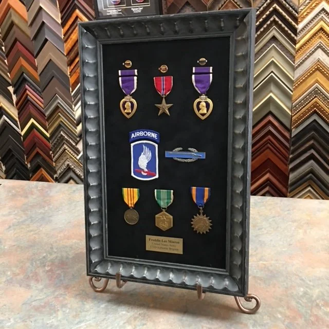 Frame displaying various military medals and patches.