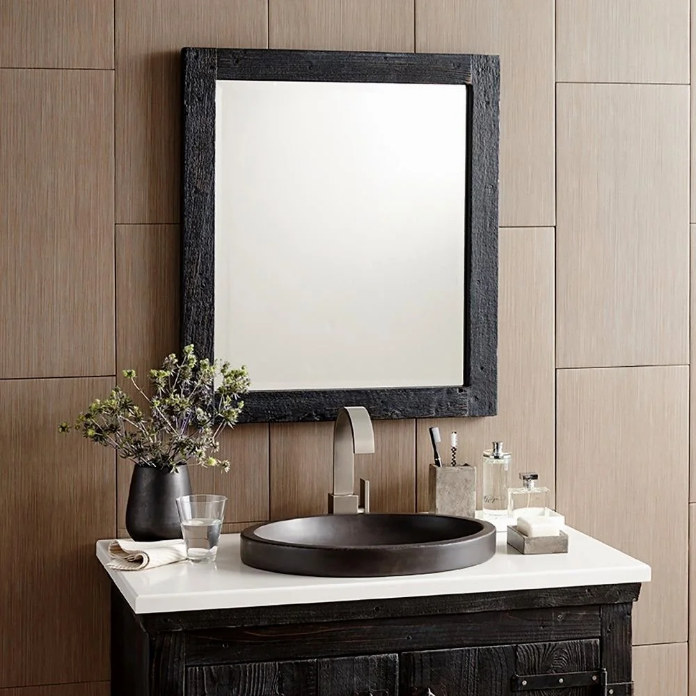 Bathroom vanity with a white countertop, black sink, and mirror, decorated with flowers, soap, and toiletries. Expert custom mirror framing in Salem, VA, and near Roanoke, VA.