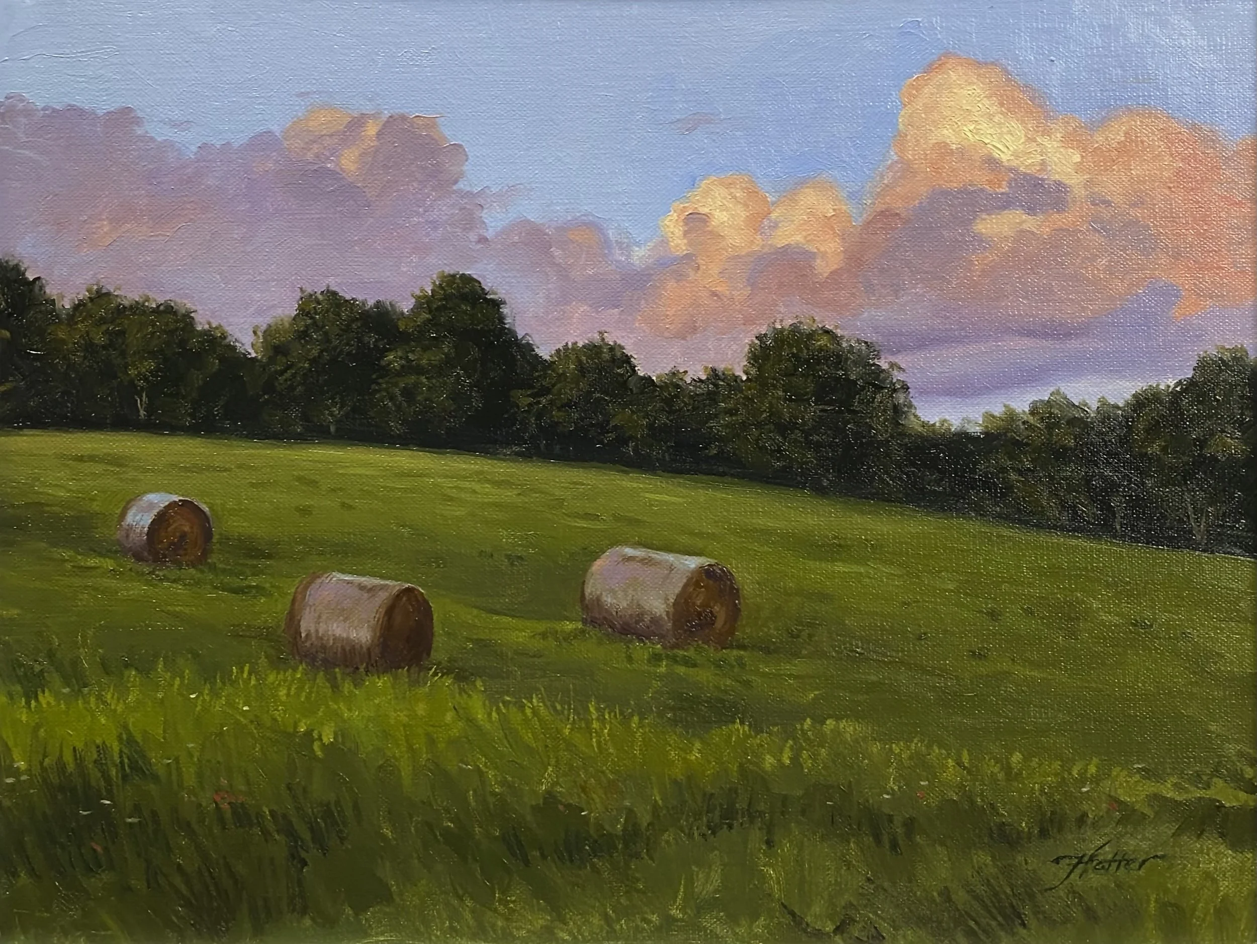 Oil painting of a green field with three hay bales, dark trees in the background, and a colorful sky with clouds at sunset.