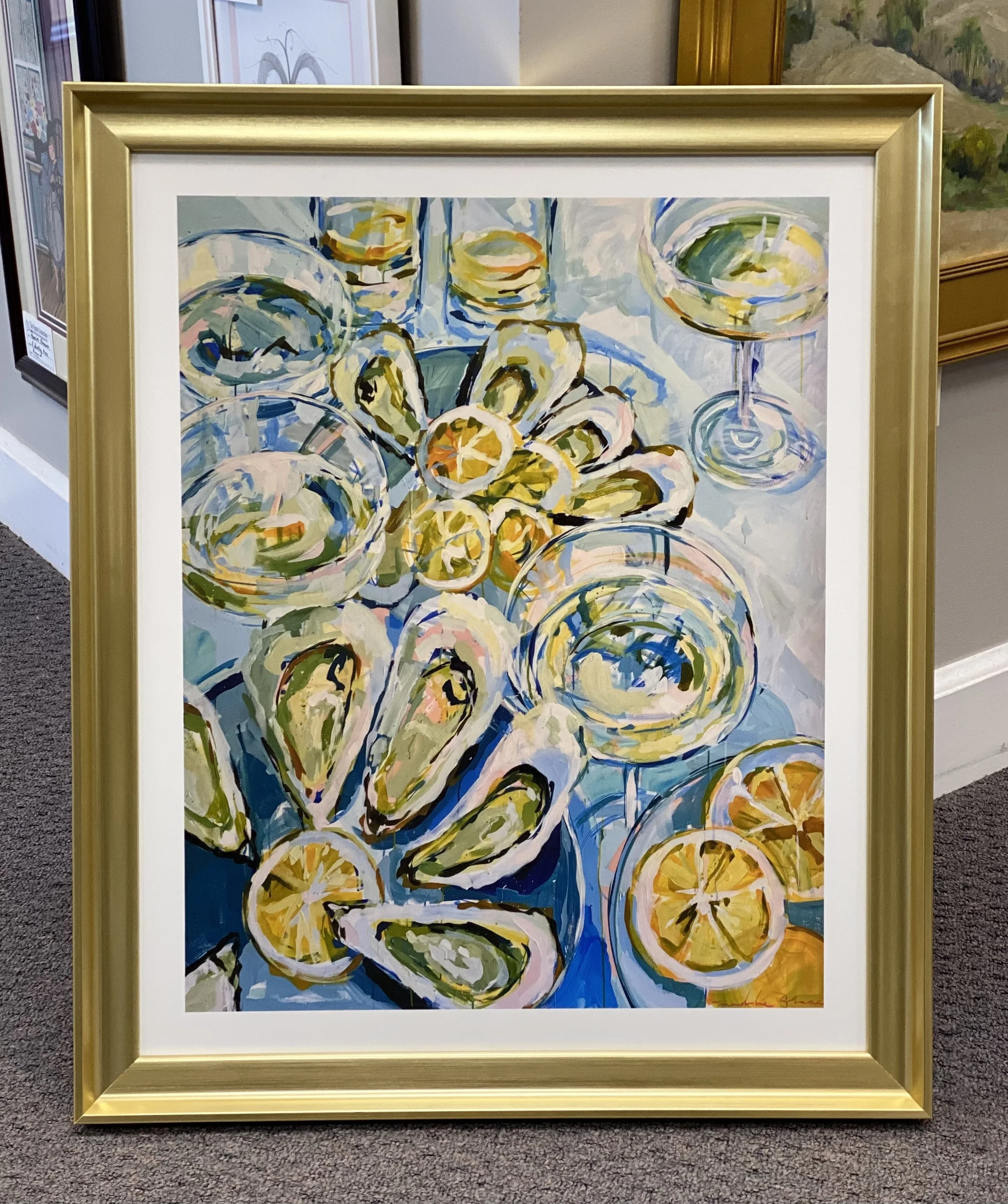 A colorful abstract painting of lemon slices in glass bowls, with bold brushstrokes and vibrant hues, framed in gold, displayed in an art gallery.