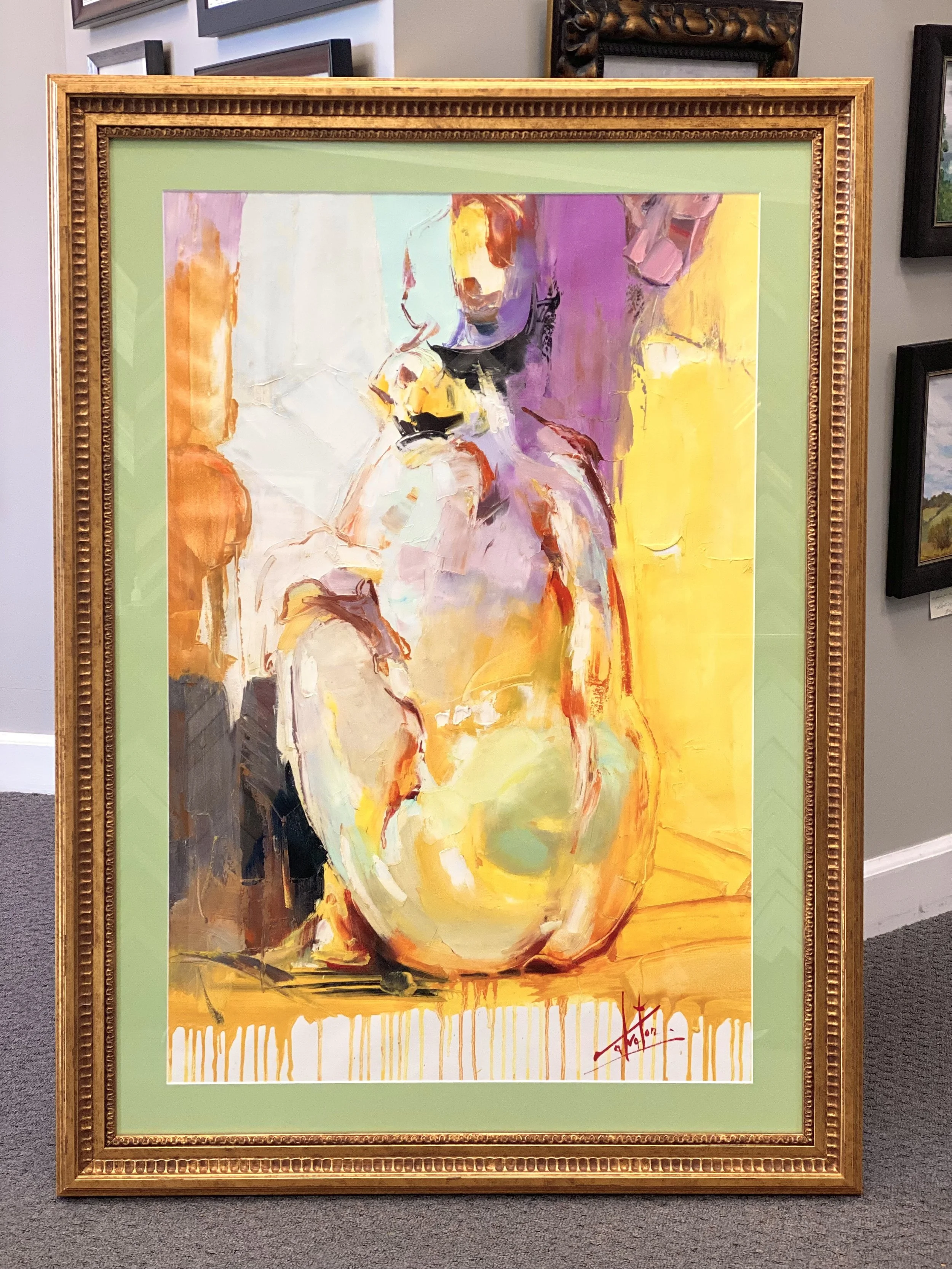 An abstract painting of a woman with a hat, painted with bold brushstrokes in orange, purple, black, and yellow tones, framed in an ornate gold frame and displayed on a gallery wall.