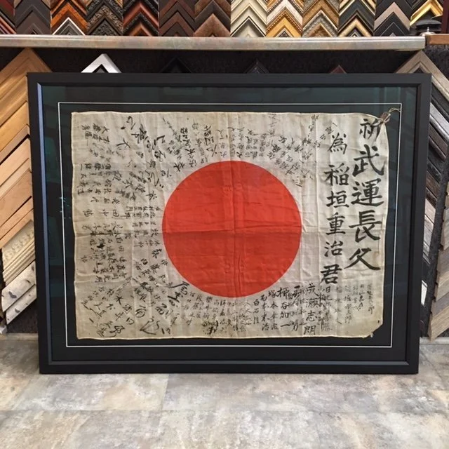 Framed Japanese flag with handwritten signatures and messages around the red circle.