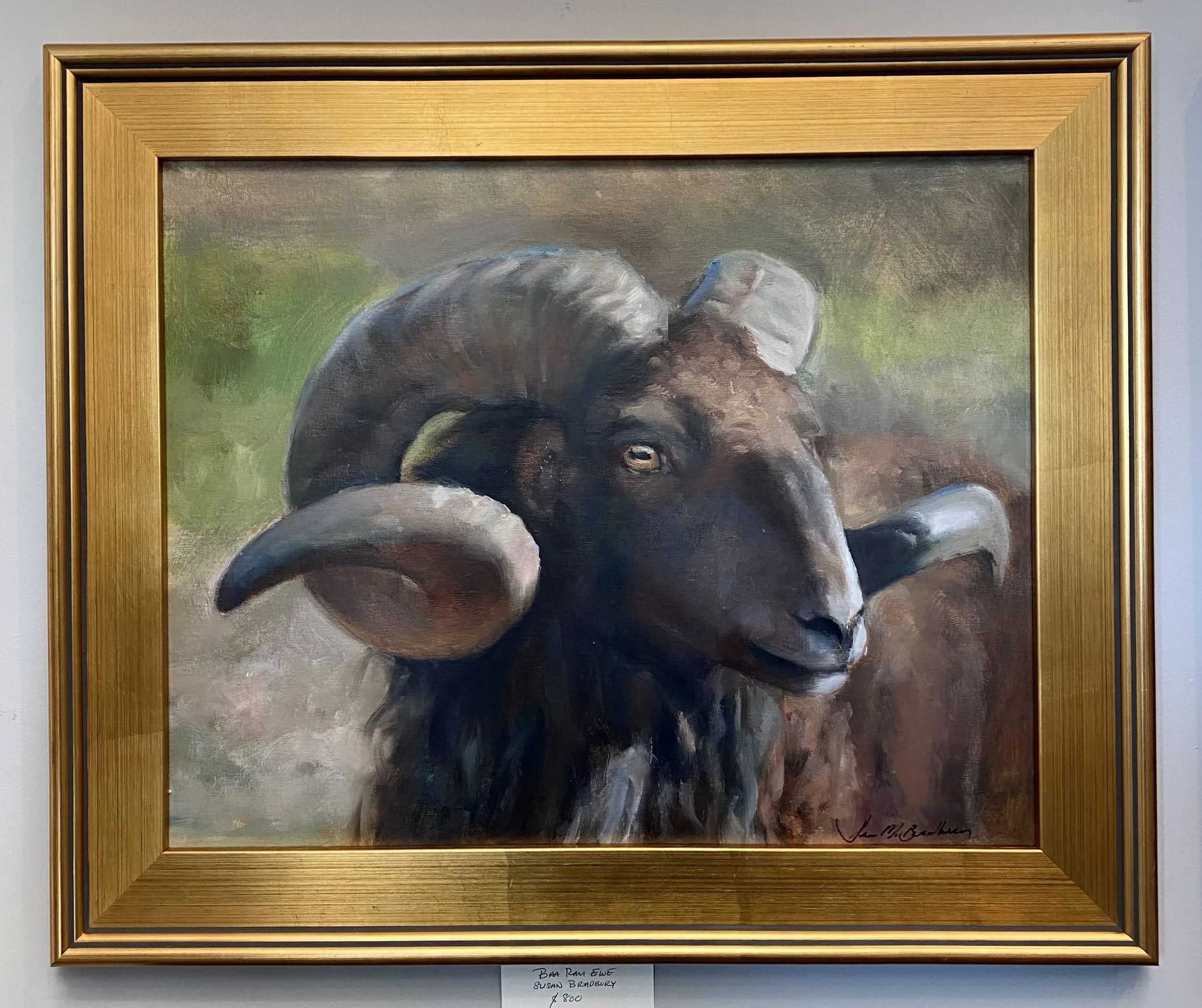 Painting of a bighorn sheep with large, curved horns, signed by the artist, in a gold frame.