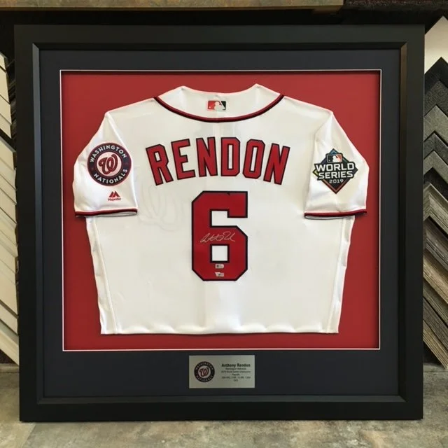 Framed Washington Nationals baseball jersey with the name "Rendon" and the number "6", featuring a World Series patch, displayed against a red background.