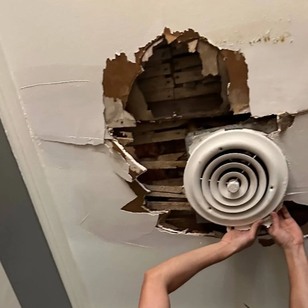 Vintage air conditioner vent being repaired after leaking roof damaged bathroom ceiling in historical home