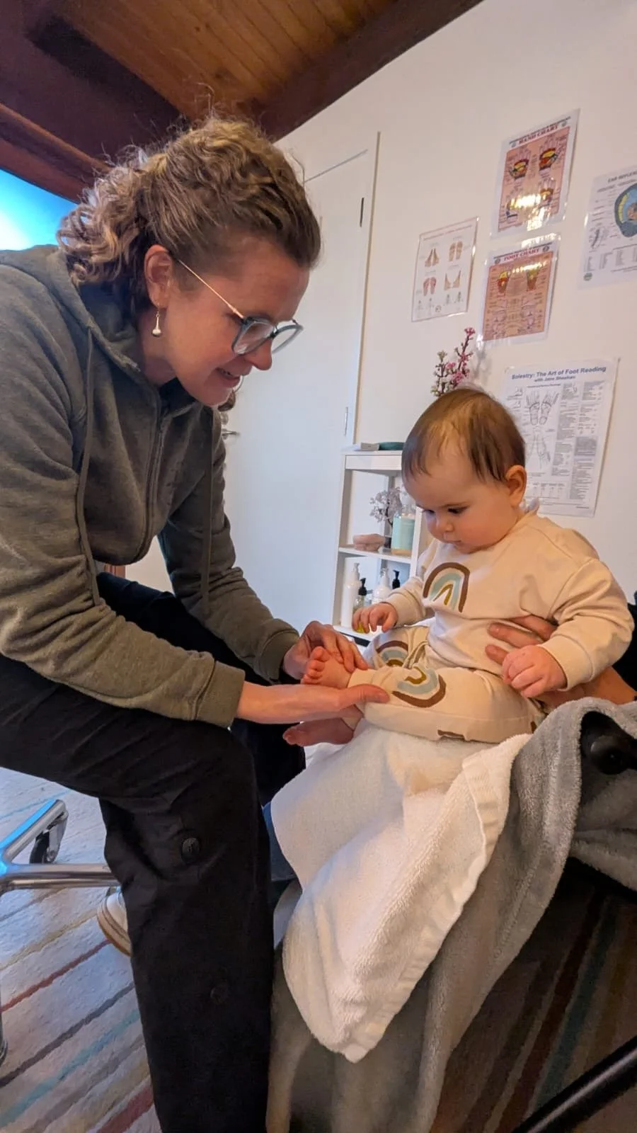 A woman holding a baby's foot during a foot reading appointment at a clinic or wellness center.
