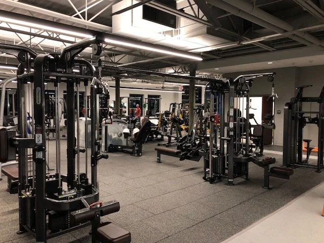 Interior of a modern gym with various workout machines and equipment.