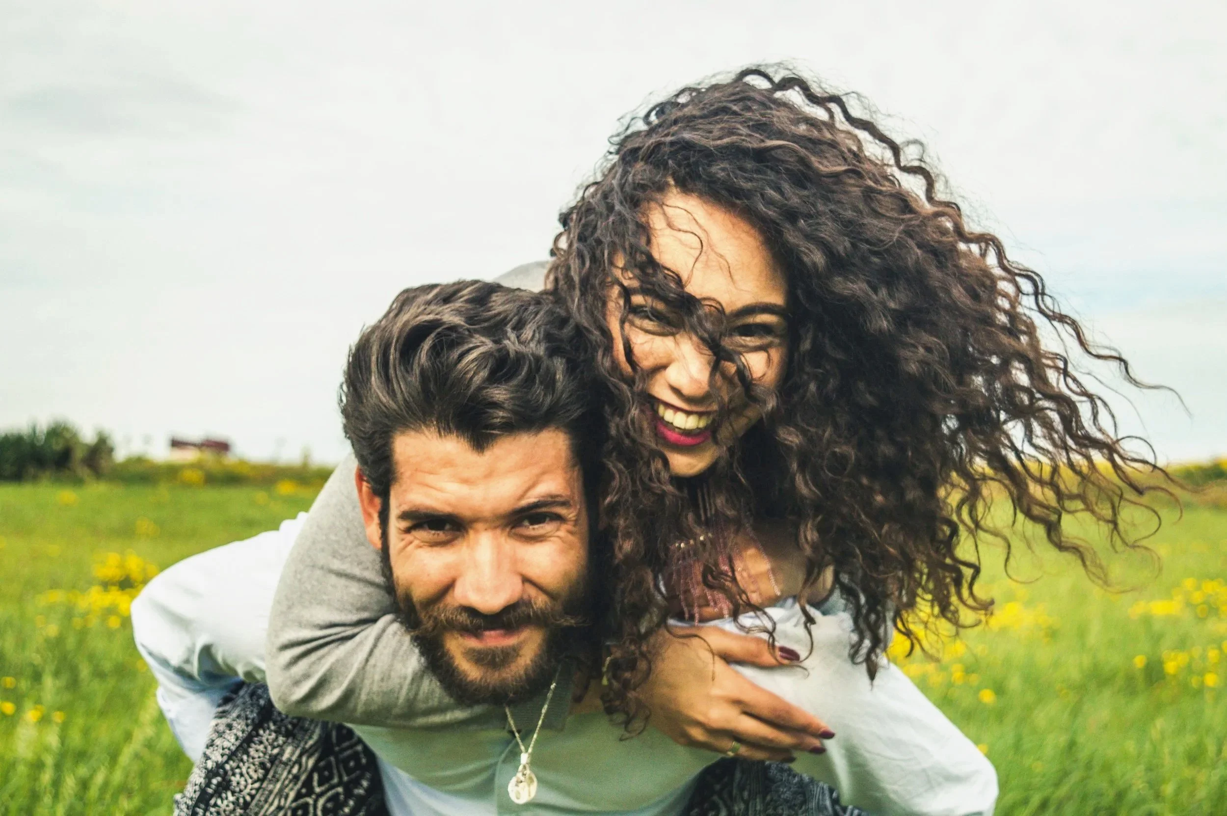 A couple holding hands in a field with warm sunlight shining behind them