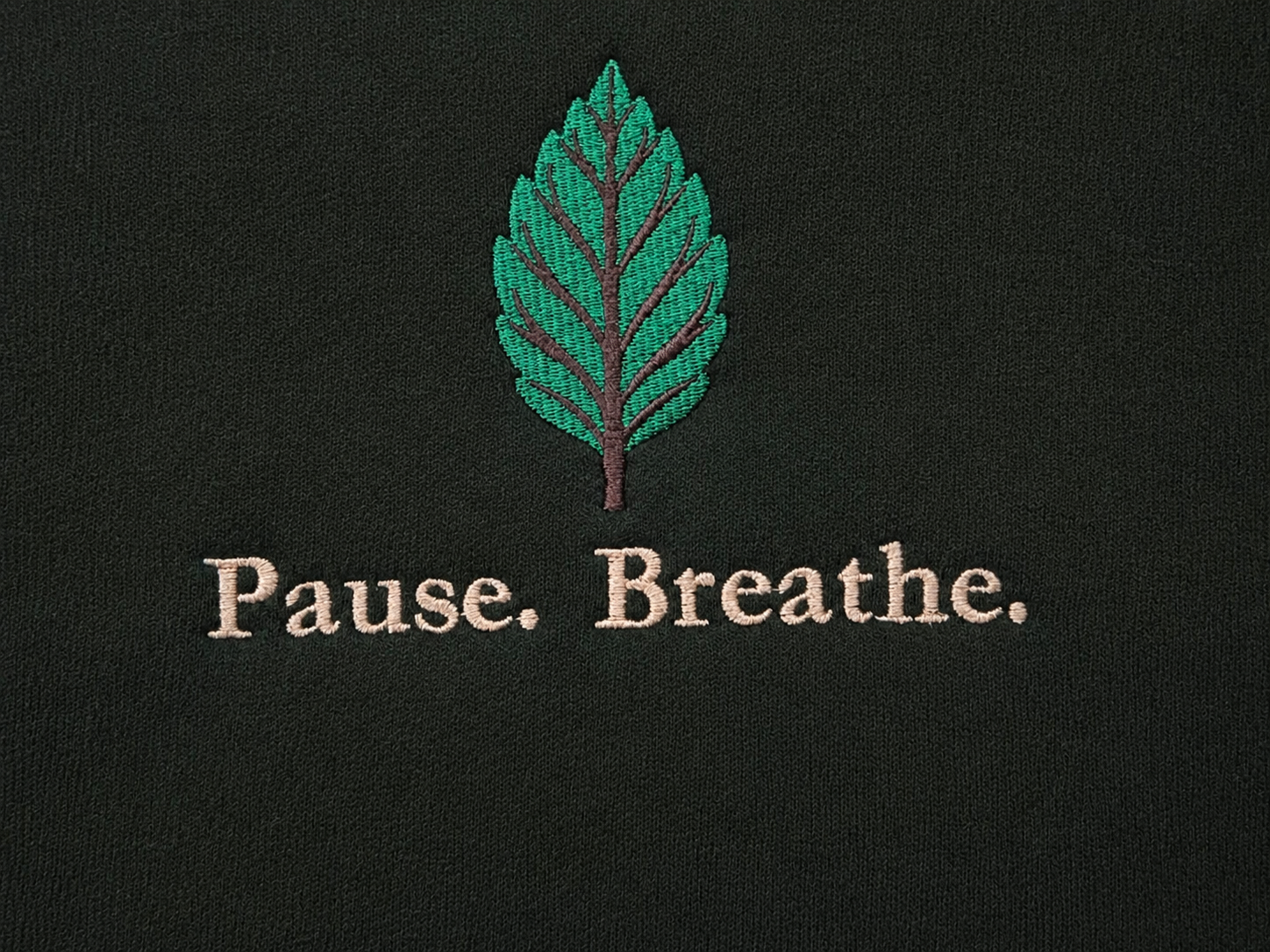 Close-up of Keeper of Calm™ leaf embroidery and Pause. Breathe. stitching