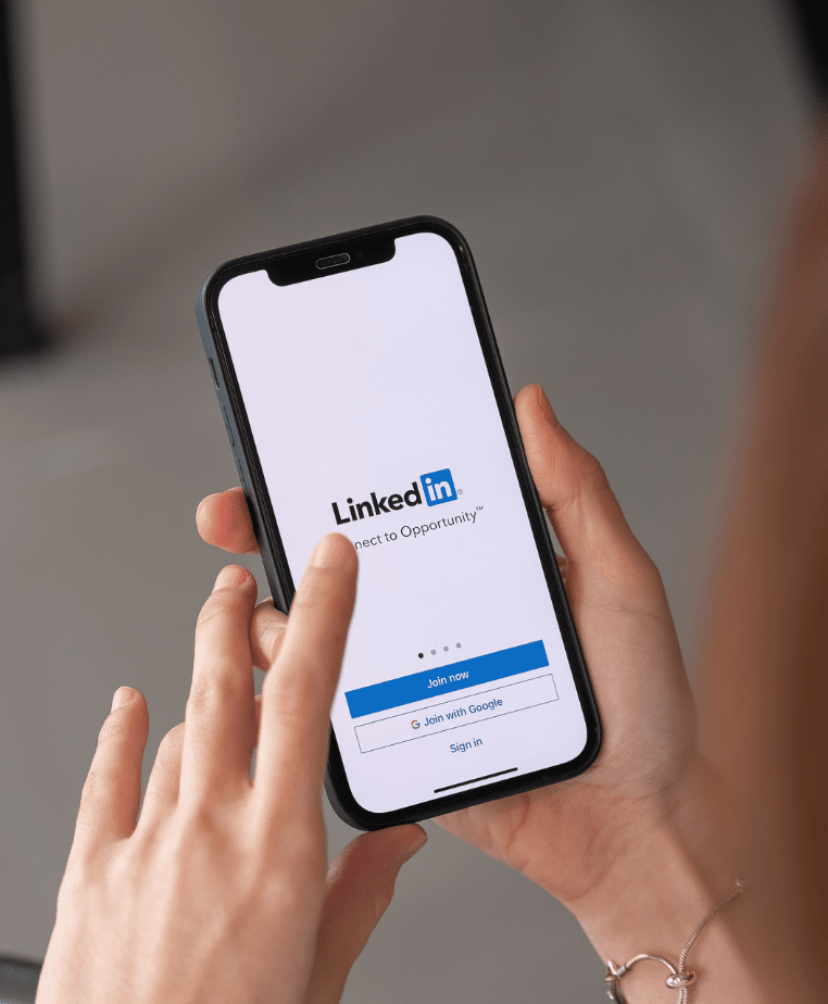 Person holding a smartphone displaying the LinkedIn app login screen emphasizing the ability to "Connect to Opportunities"