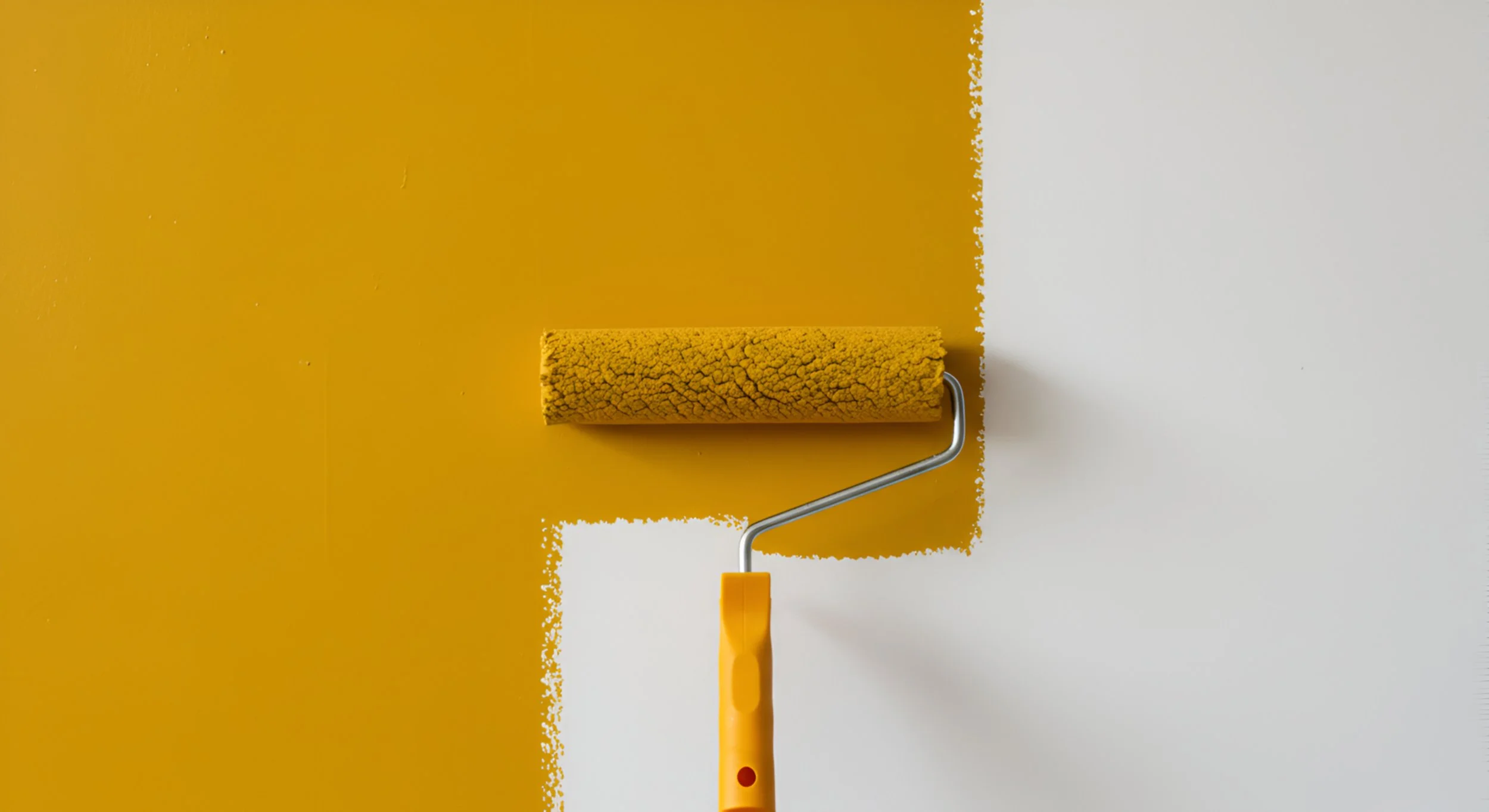 A paint roller with a yellow handle applying yellow paint onto a white wall.