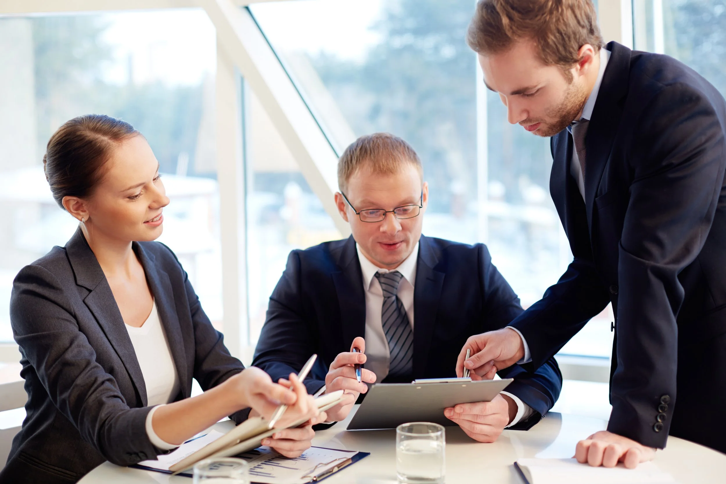 a group of one business woman and 2 business men discussing a project