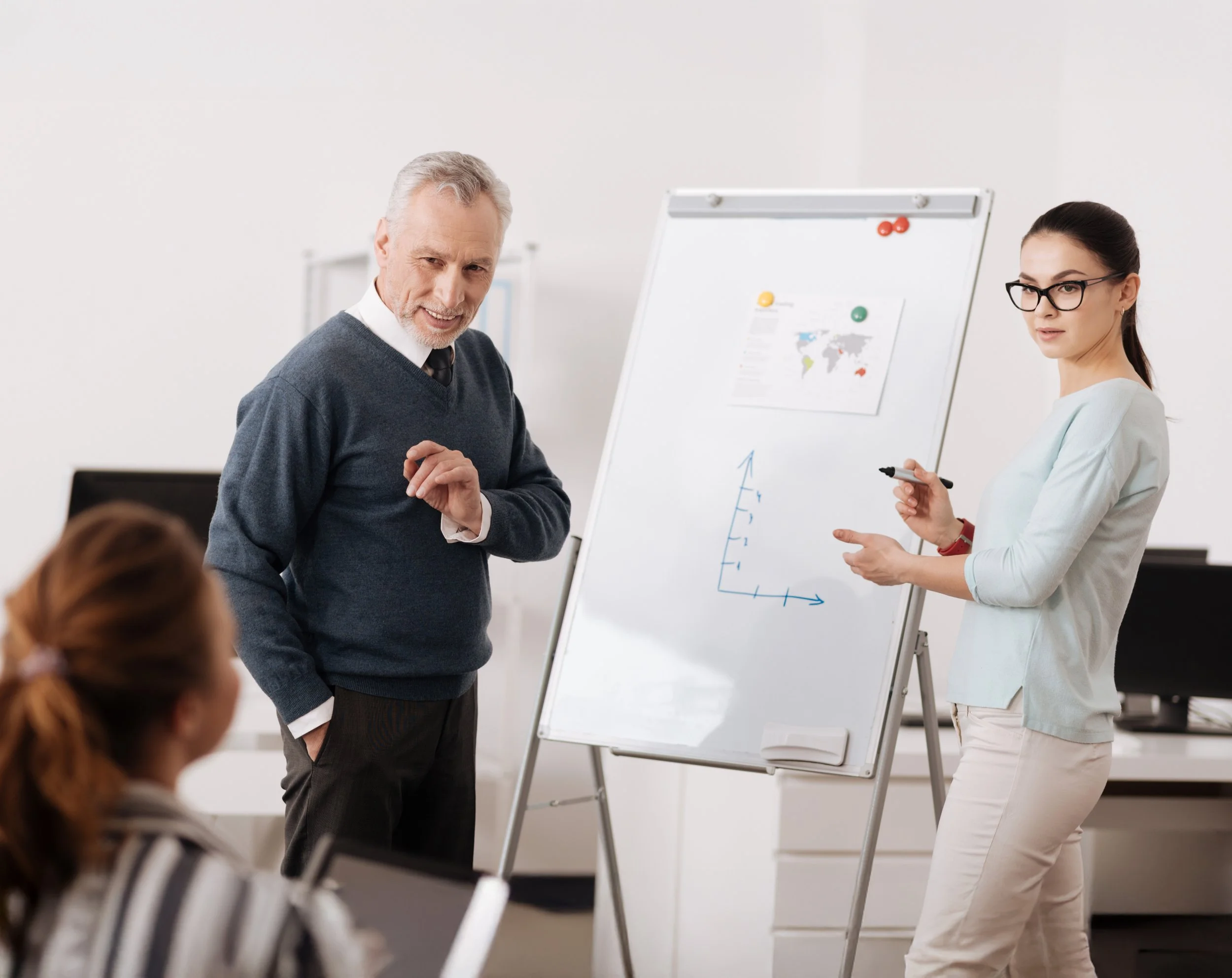 Organisational Support represented by a woman and mature man presenting a graph on a whiteboard in a classroom, with another woman watching.