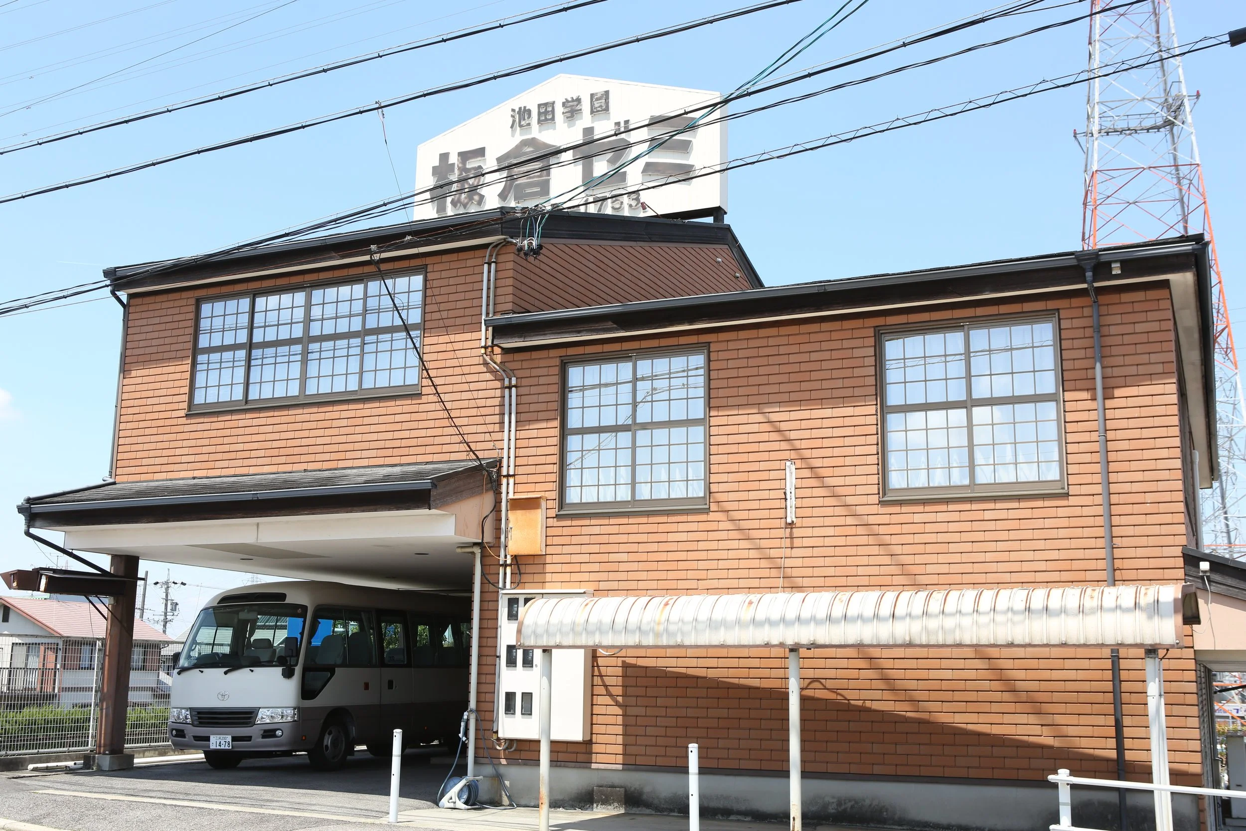 赤レンガ調の二階建ての建物。車庫にバスが停車している。屋根にはアーチ型のカバーがついている。大きな窓が複数ついている。背景には通信塔と電線が見える。