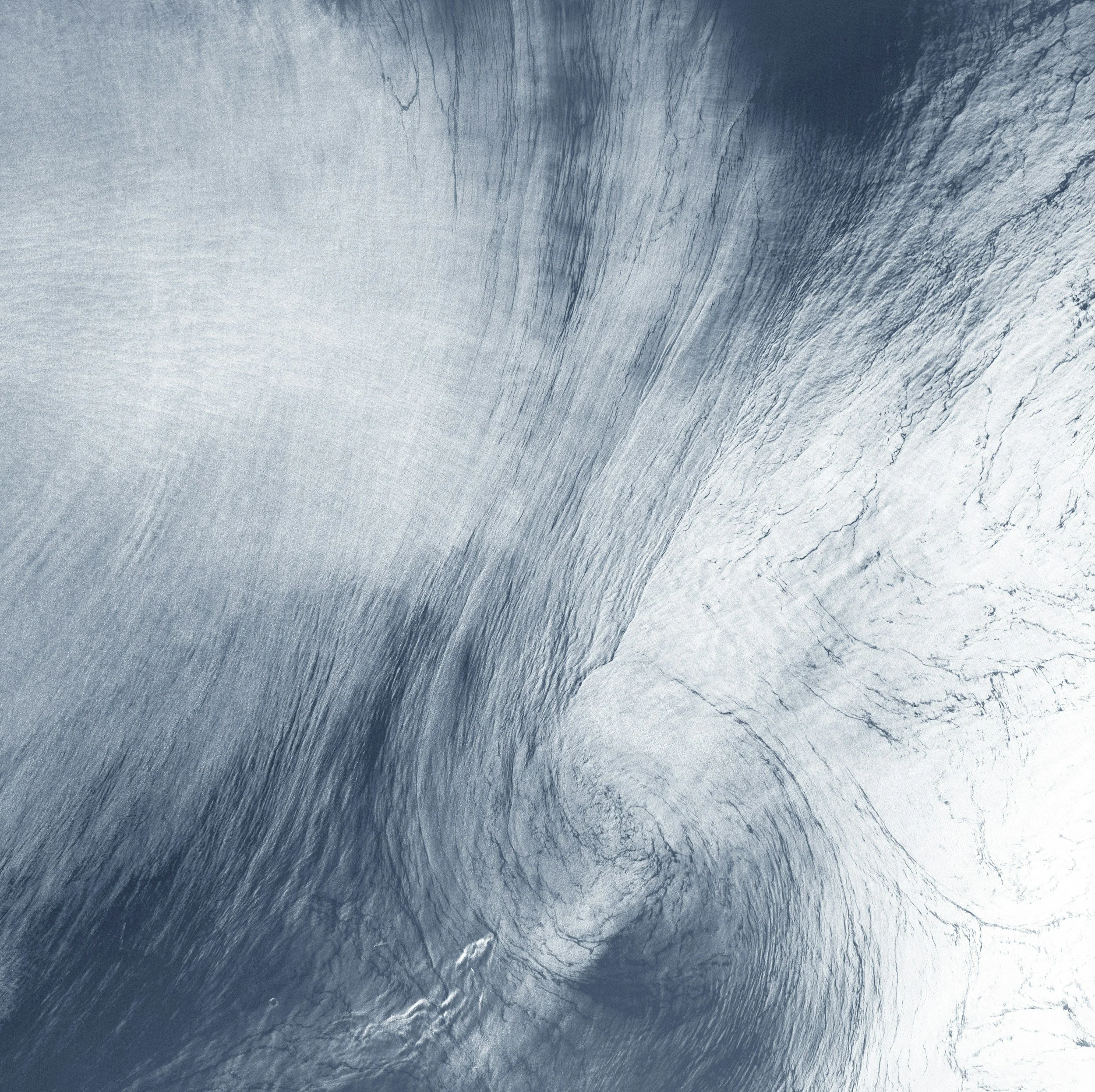 A large wave with a white crest over a blue body of water, captured from underneath the water surface.