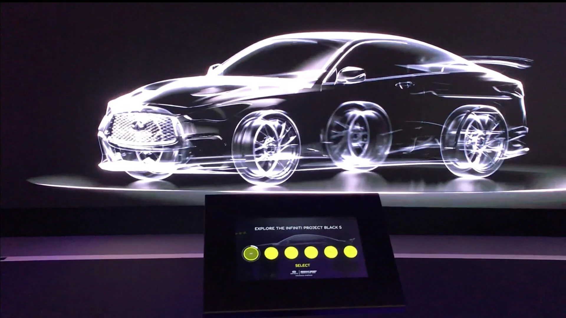 A sleek, futuristic car design on display, illuminated with glowing outlines, with a label at the bottom that says 'Explore the Infiniti Project Black 5.'