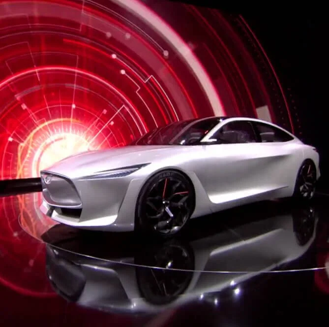 A white electric concept car displayed on a reflective surface in front of a red, digital, sci-fi background.