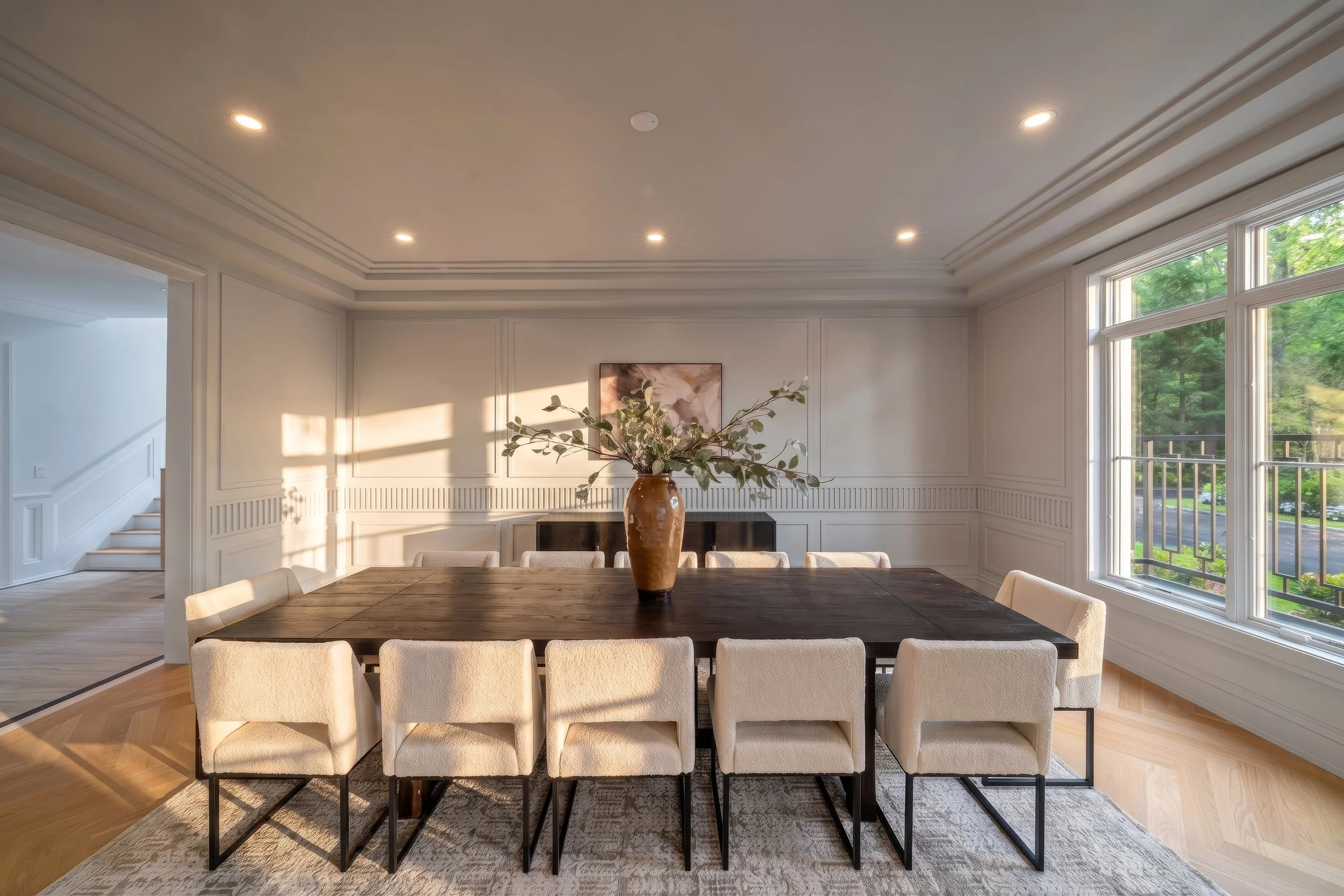 Formal dining room with long table, upholstered chairs and garden windows