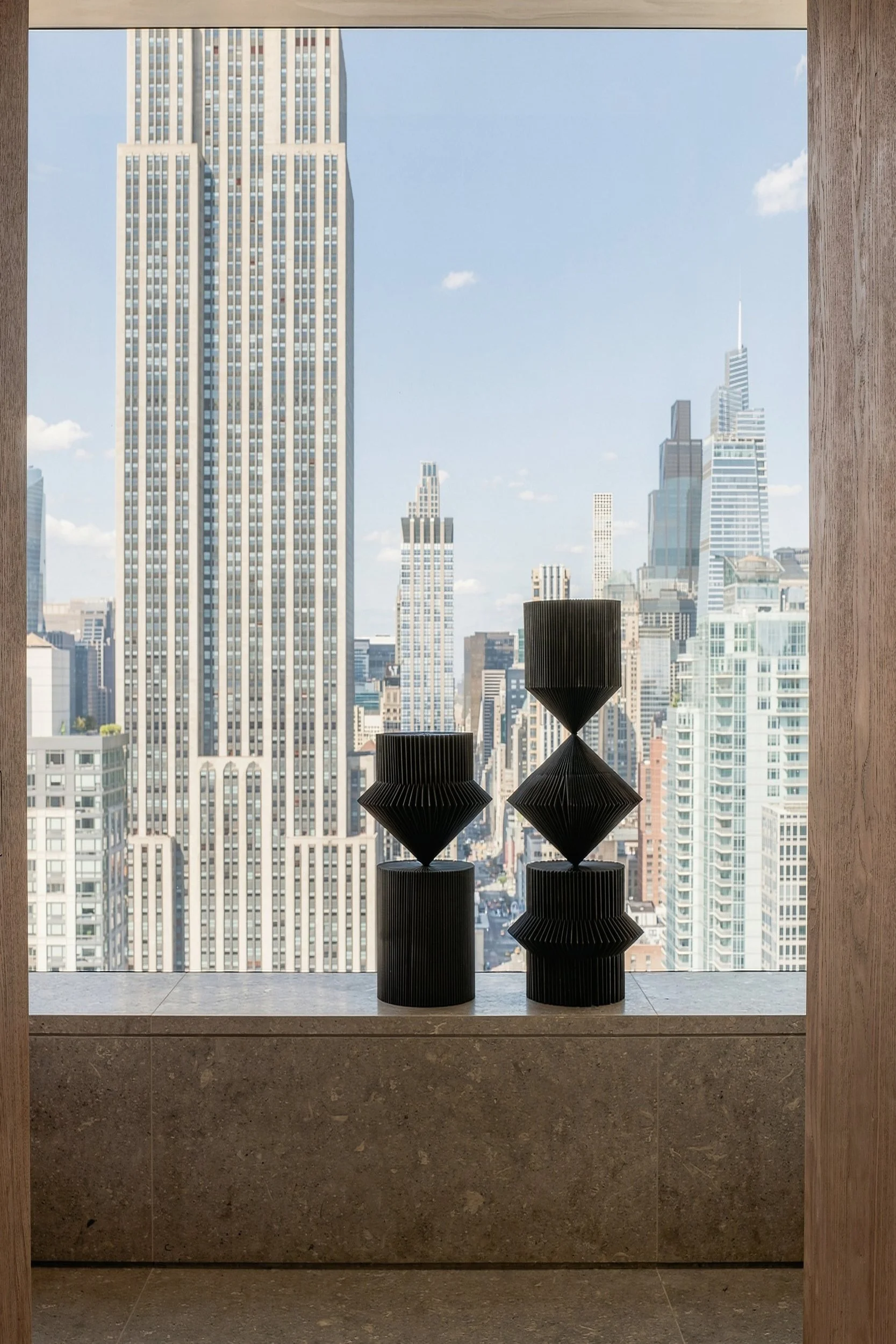 Empire State Building framed by a deep window with black sculptural objects
