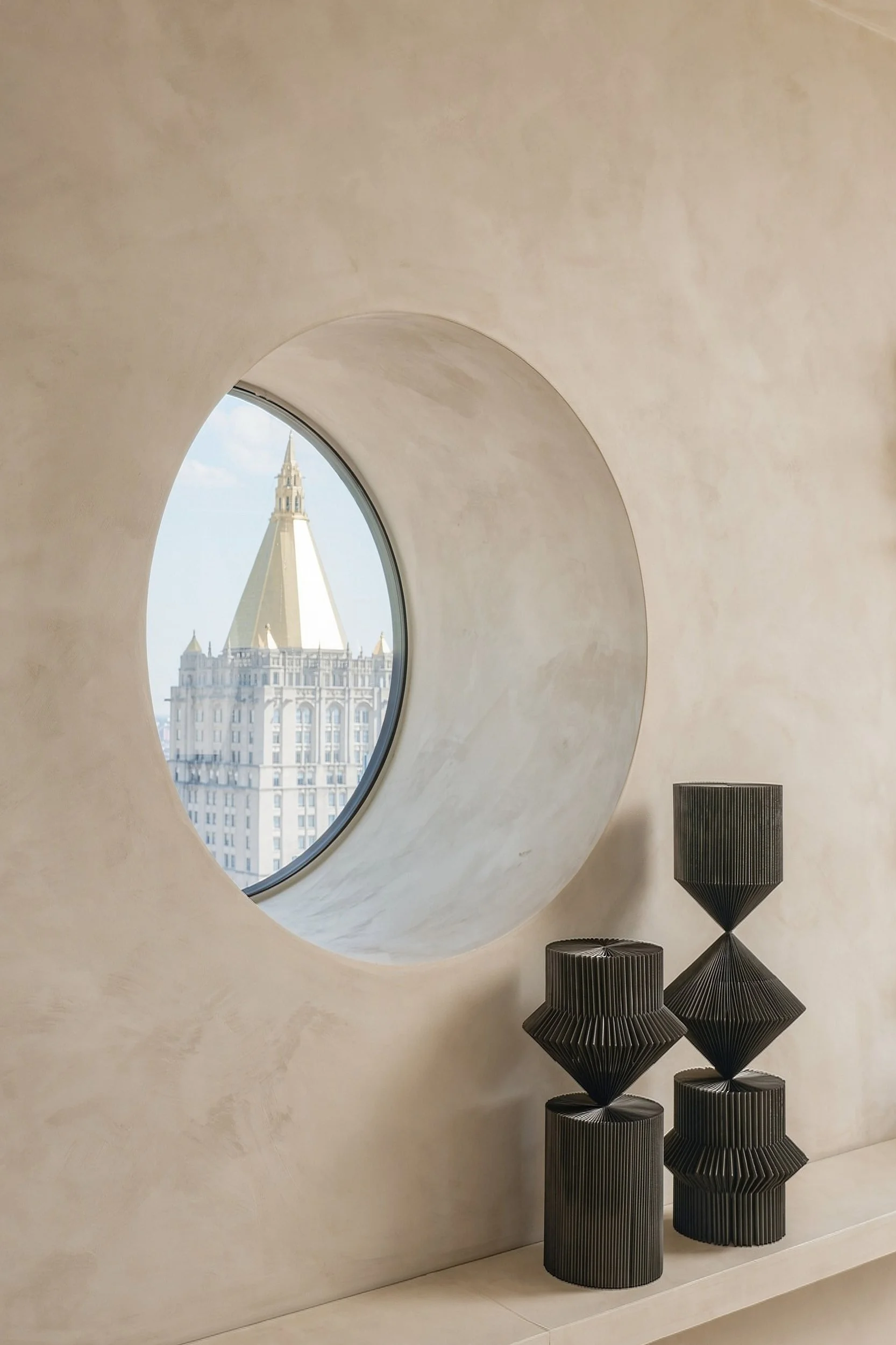 Circular window in a plaster wall with sculptural objects, architectural detail