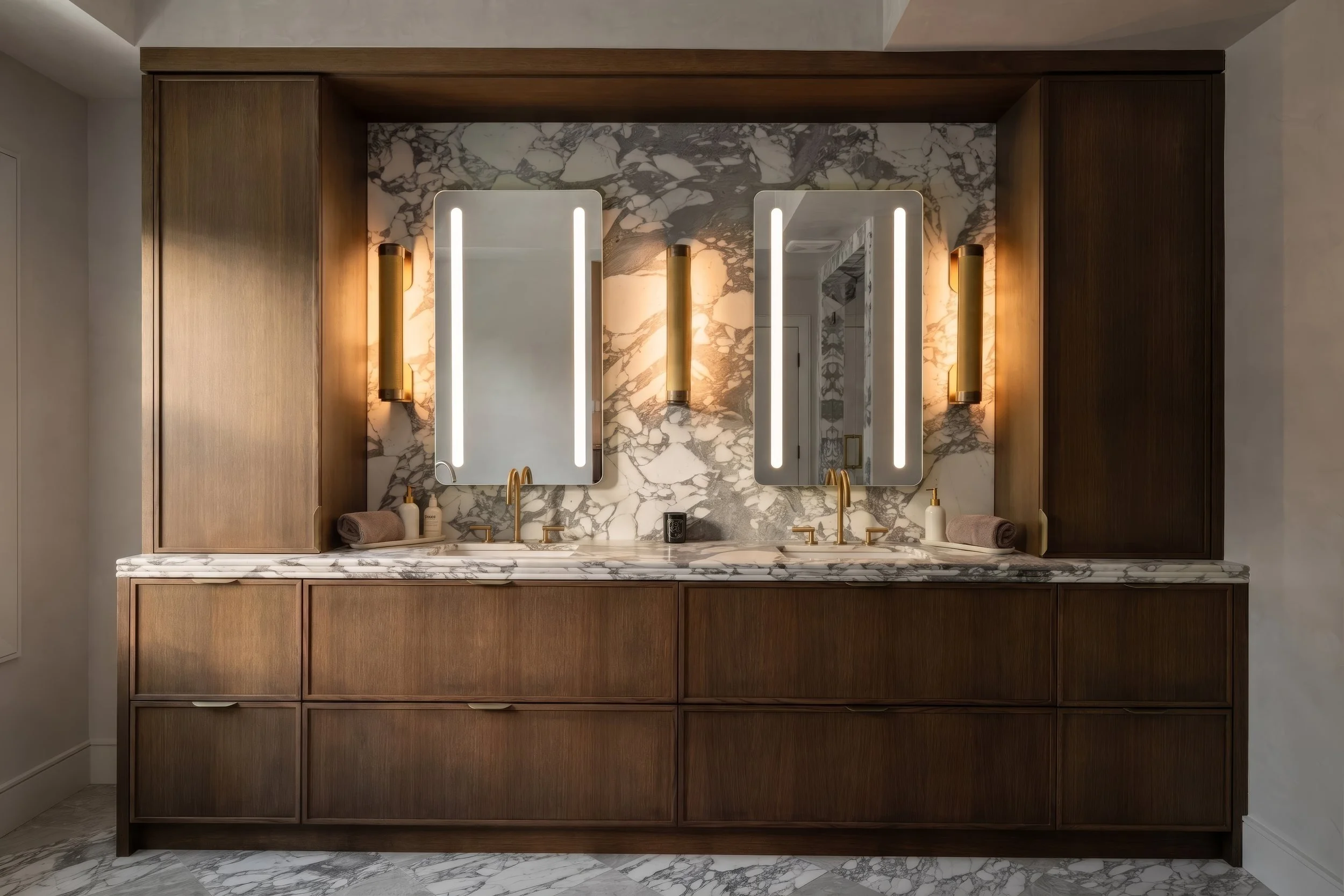 Walnut double vanity with backlit mirrors and book-matched marble wall