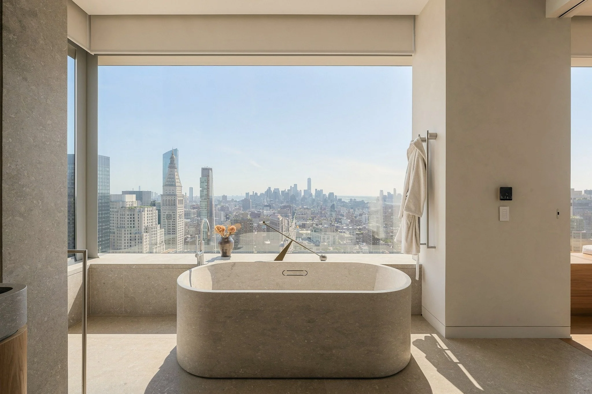 Luxury Manhattan penthouse bathroom with a stone soaking tub and skyline view, photographed by ARAZ Media