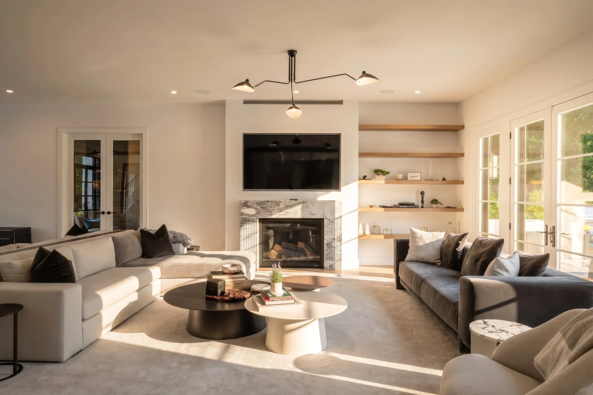 Bright living room with fireplace, built-in shelving and sculptural lighting in a luxury home