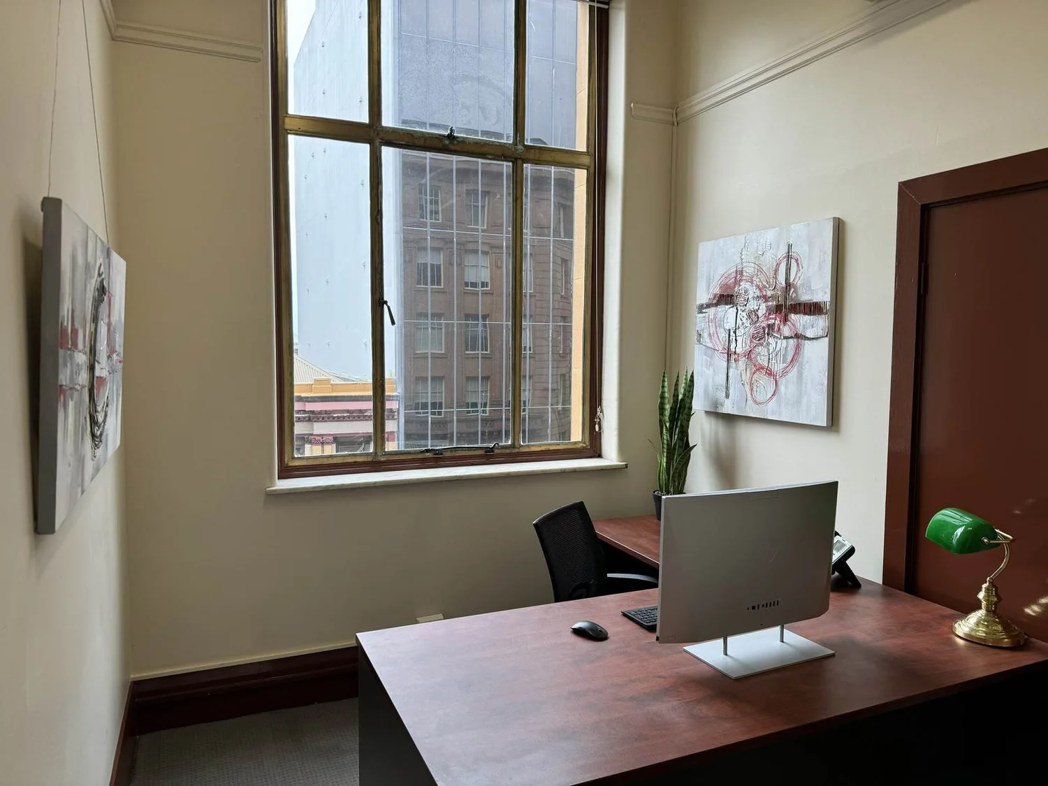 A furnished private suite with a timber desk and city outlook