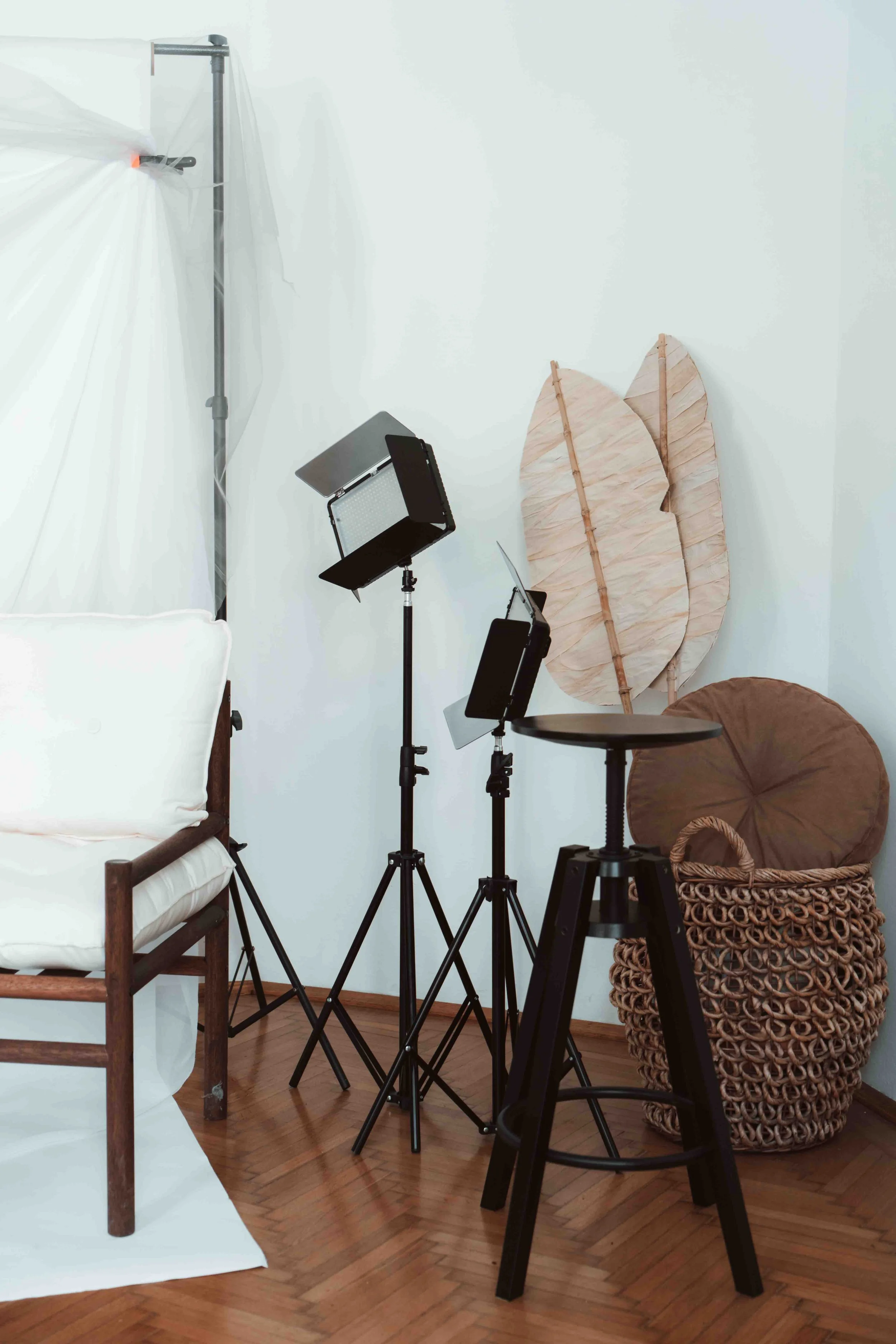 Photography studio setup with lighting equipment, backdrops, and seating, in a room with hardwood floors and white walls.