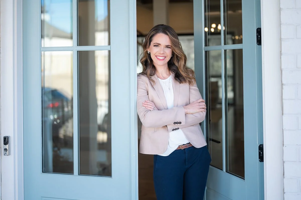 female real estate agent leaning on an open front door of a house