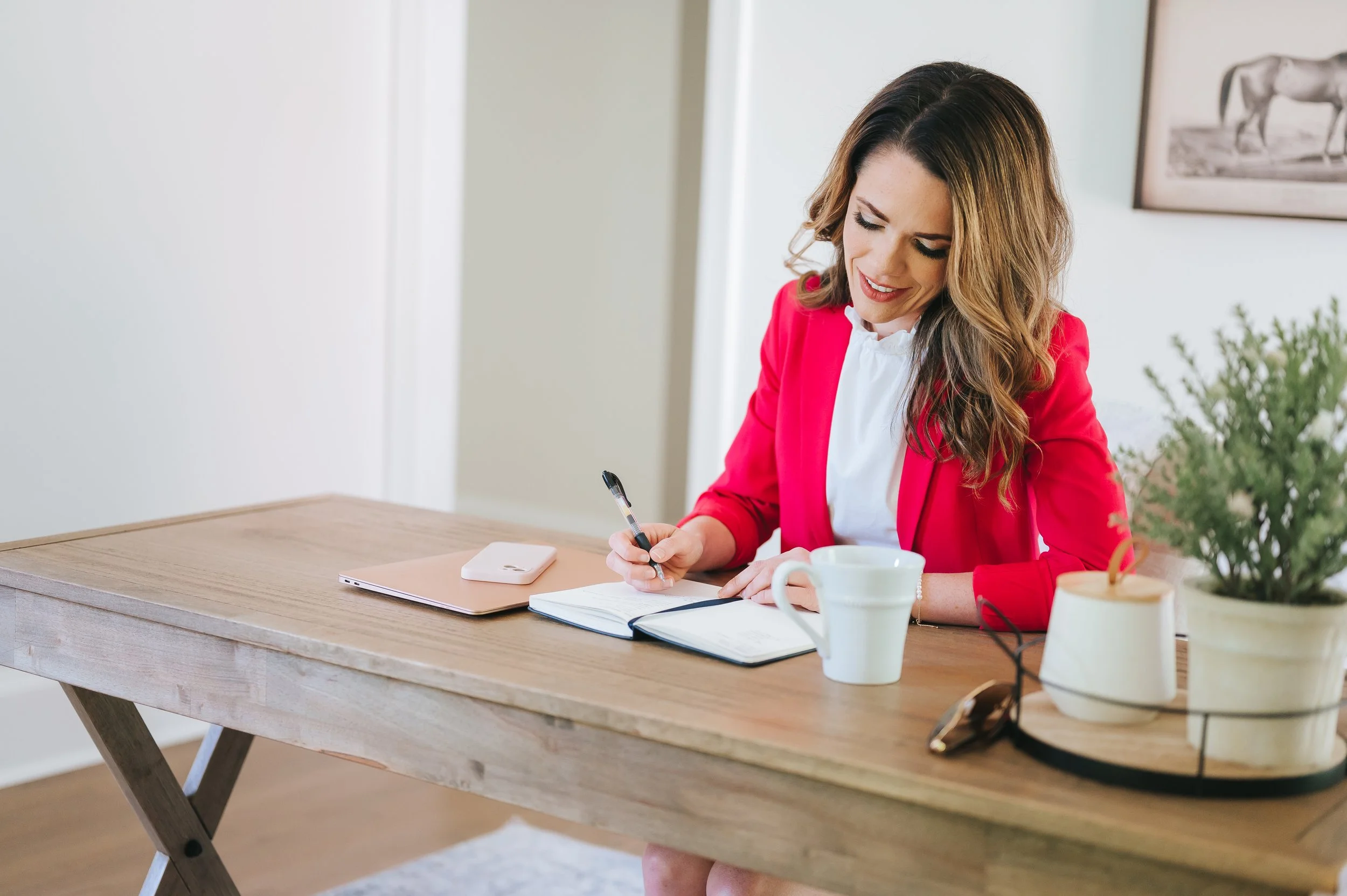 social media manager sitting at her desk and writing in a notebook