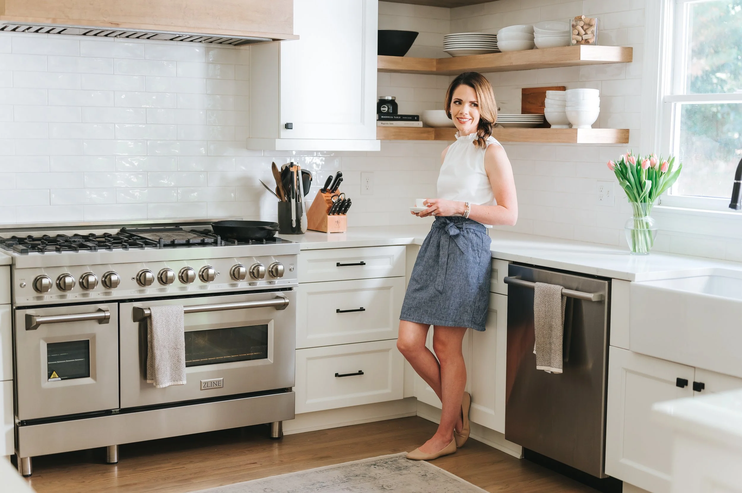 female real estate agent sipping coffee and leaning against kitchen cabinets in a luxury home