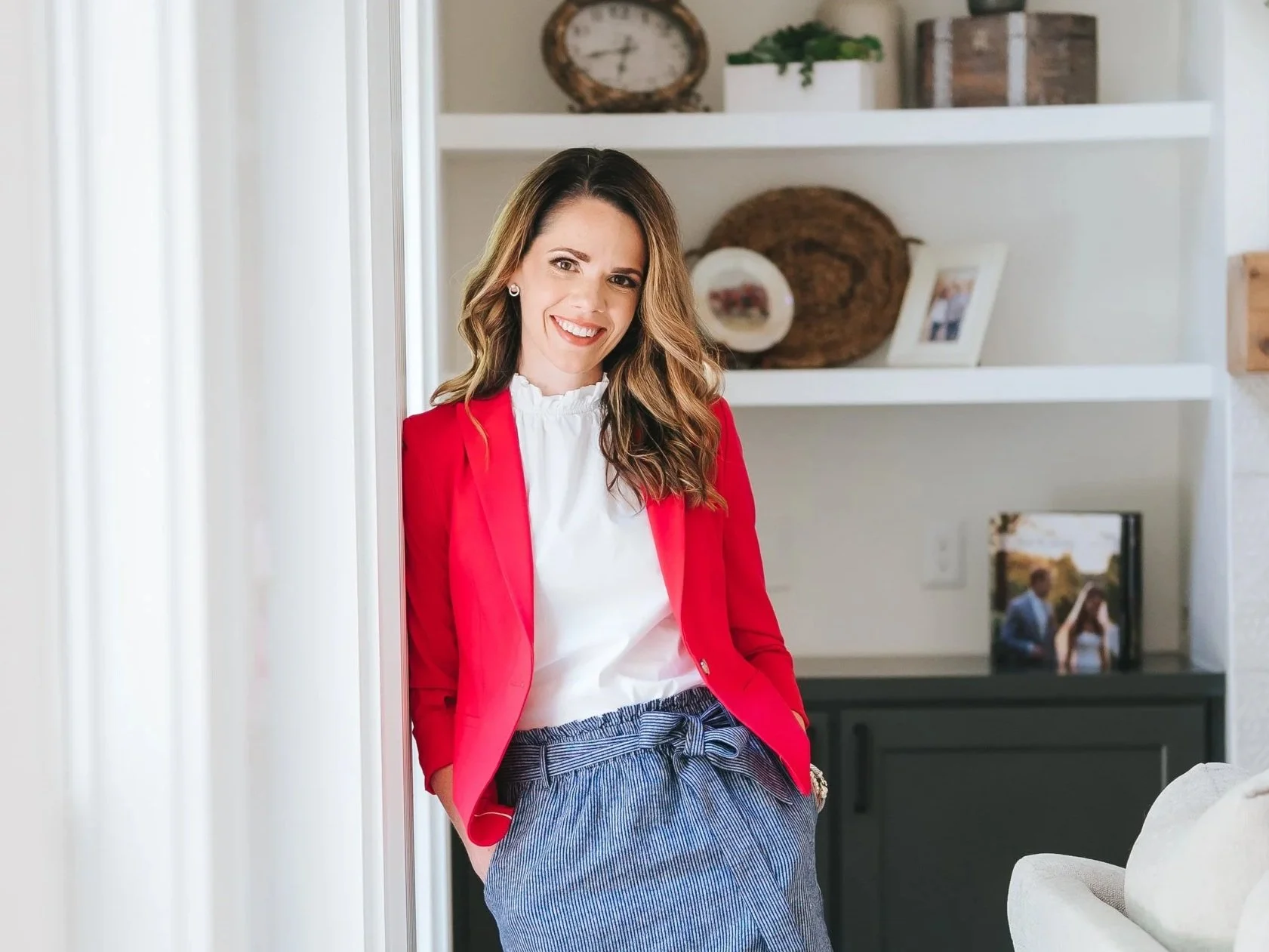female social media manager in bright pink jacket leaning against a wall in the family room
