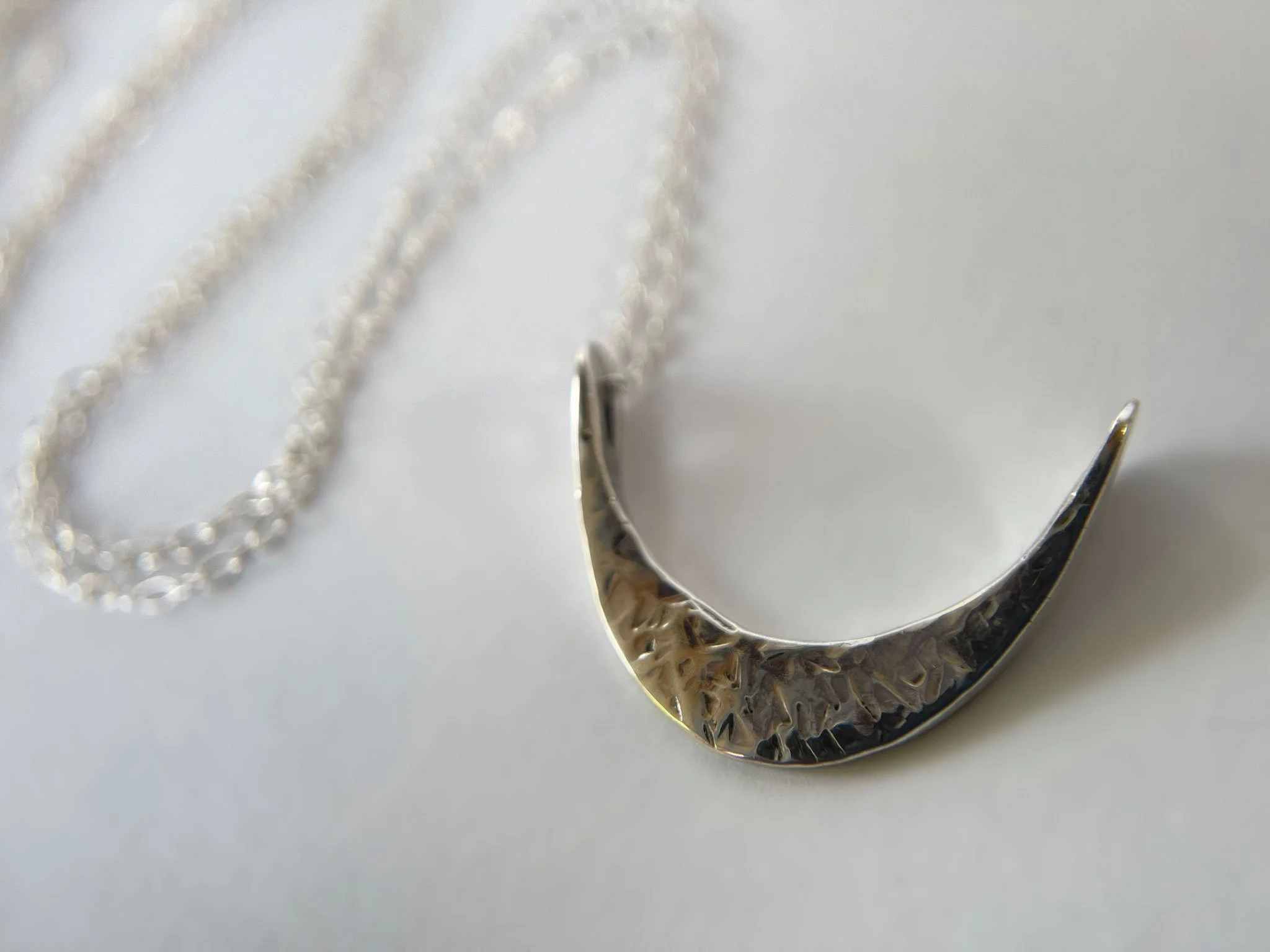 Silver crescent moon pendant on white background