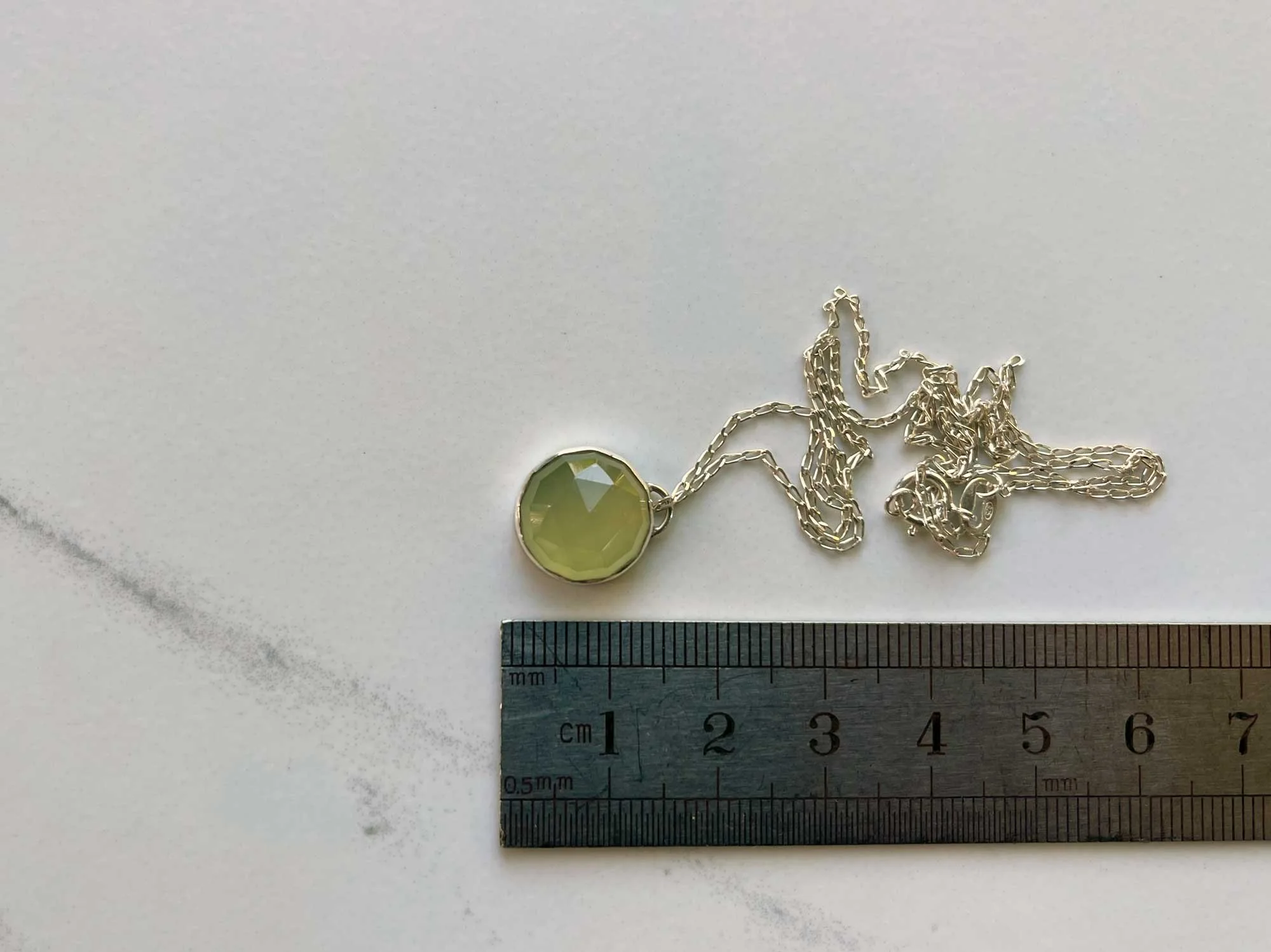 handmade green chalcedony necklace by ruler on white background