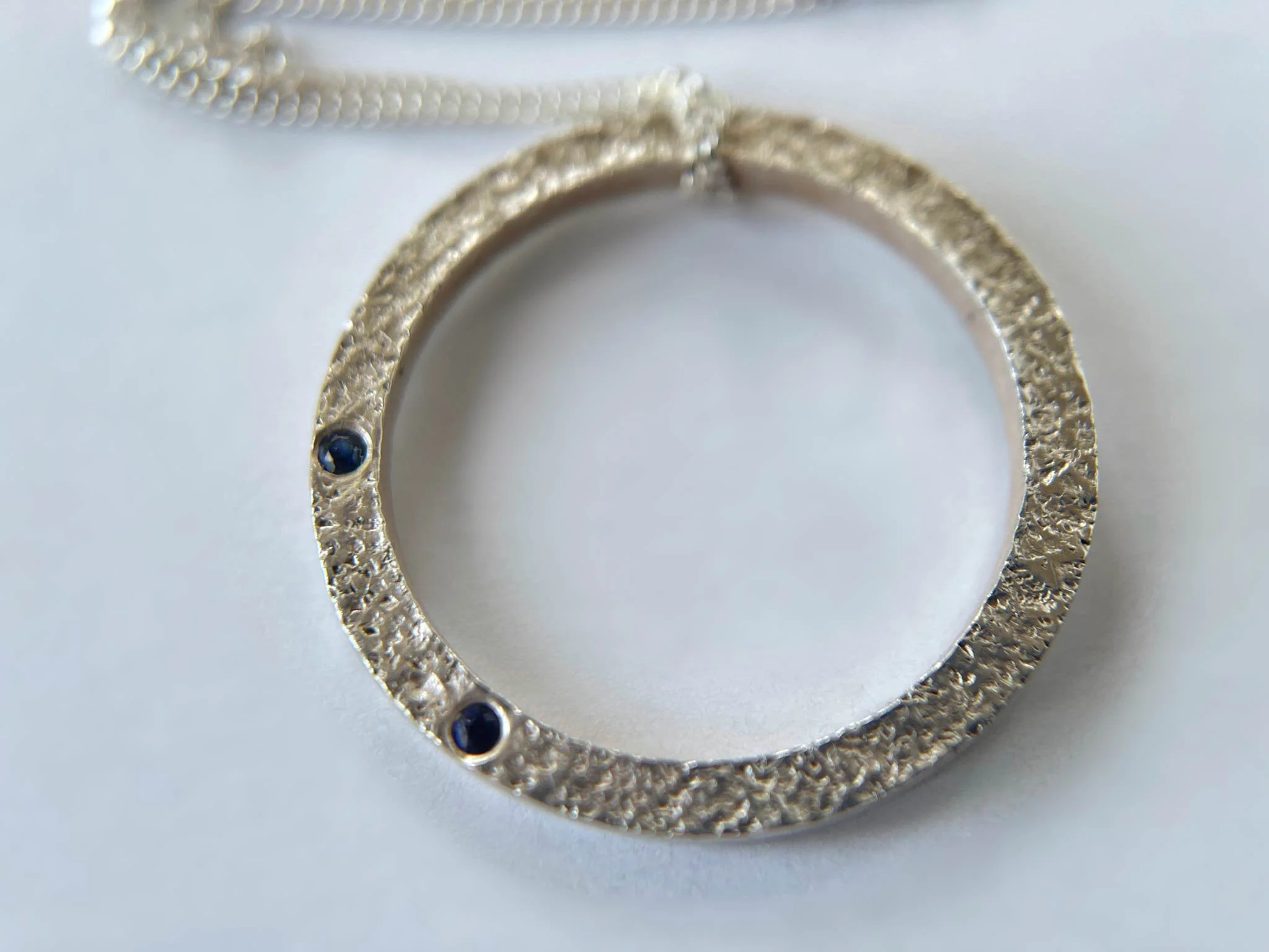 textured silver circle necklace with sapphires close up