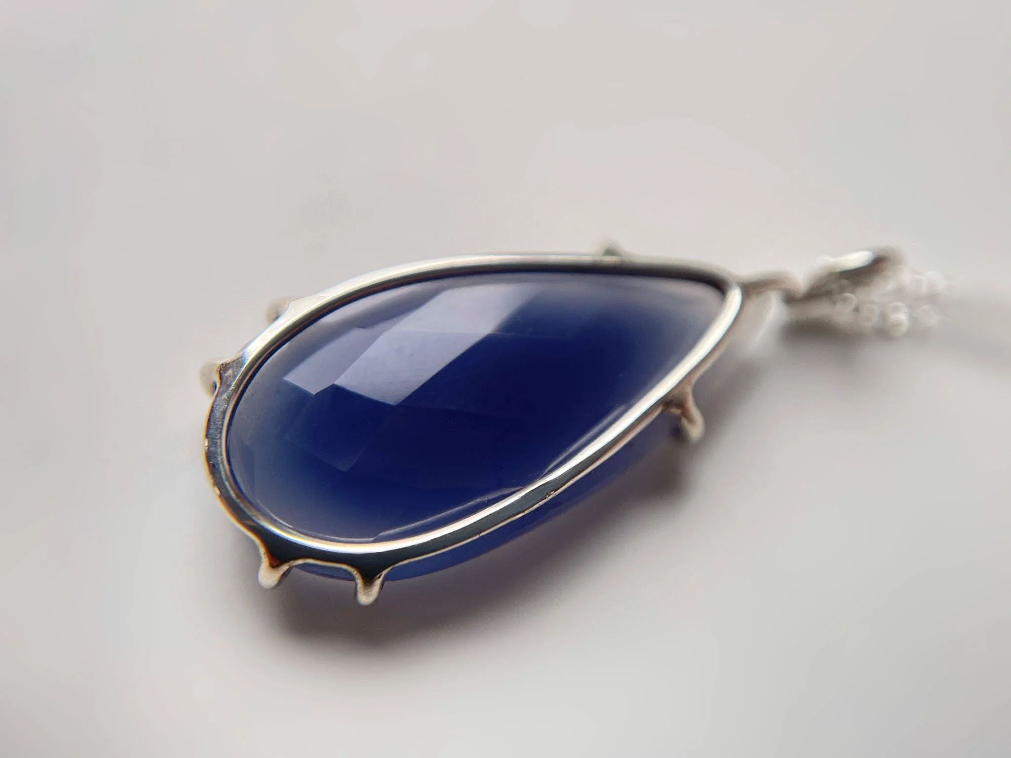 rose cut blue chalcedony gemstone in a handmade claw setting white background