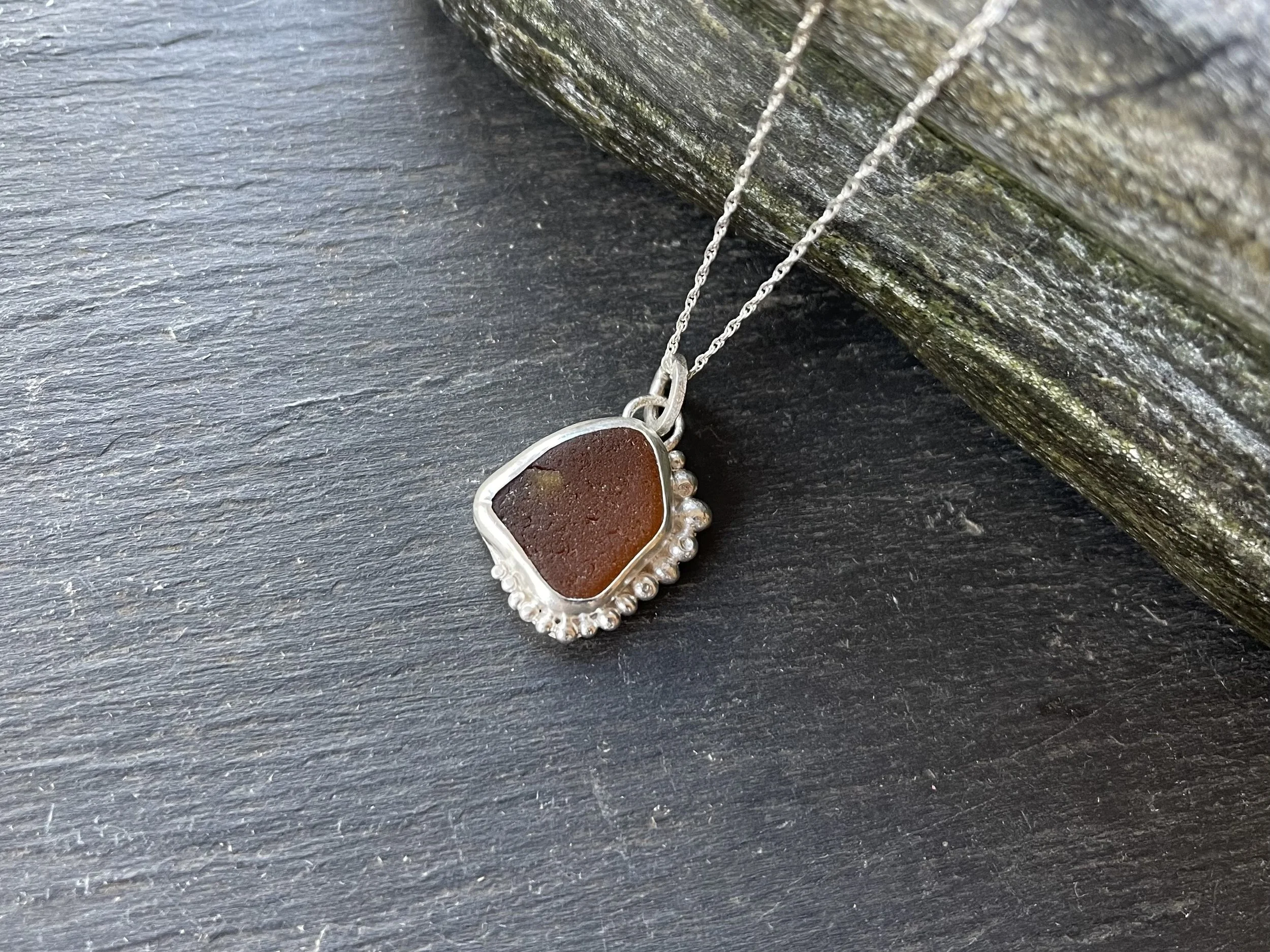 Natural amber sea glass pendant grey background