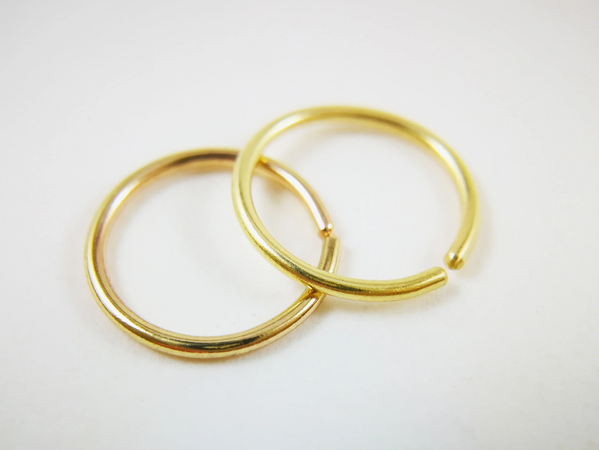18k and 14k gold conch hoops on white background