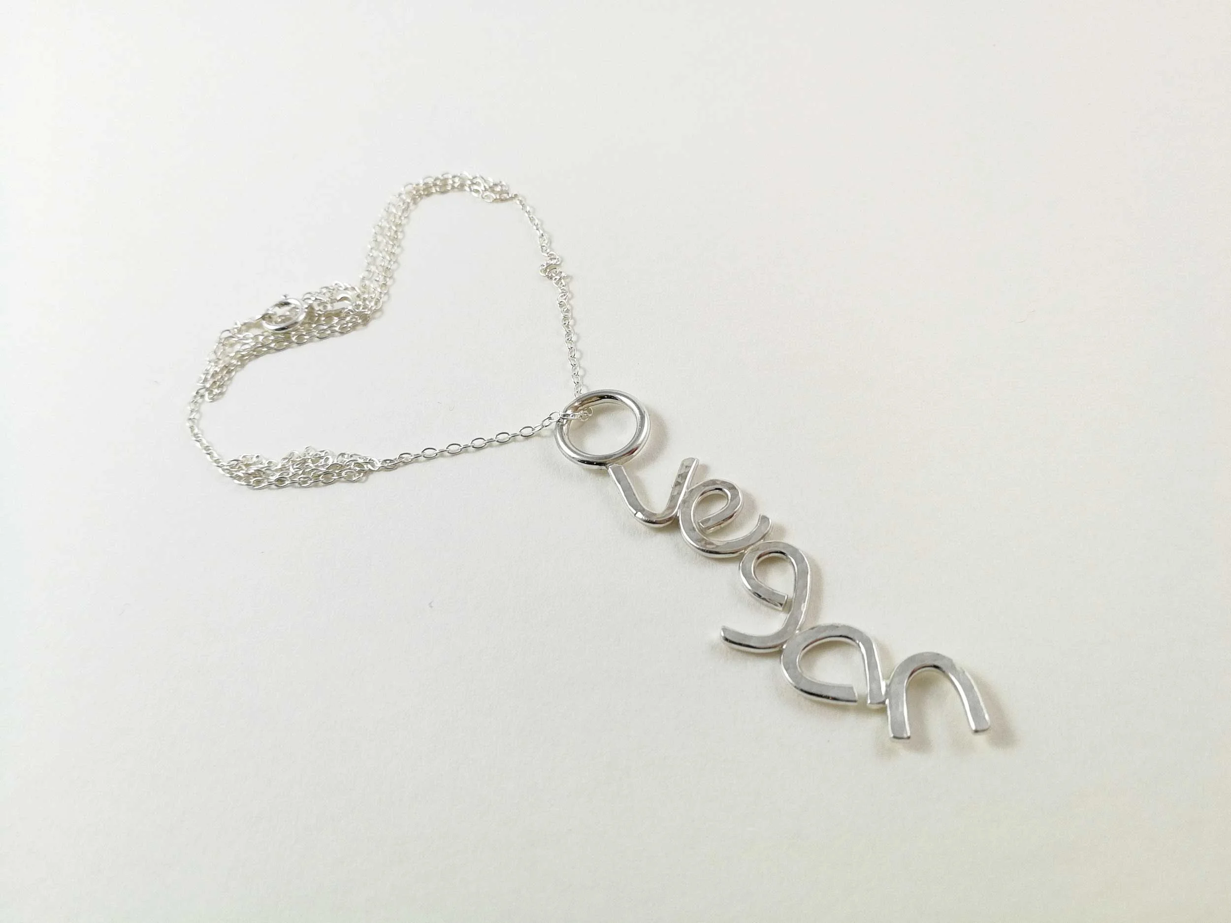 handmade silver vegan pendant on white background