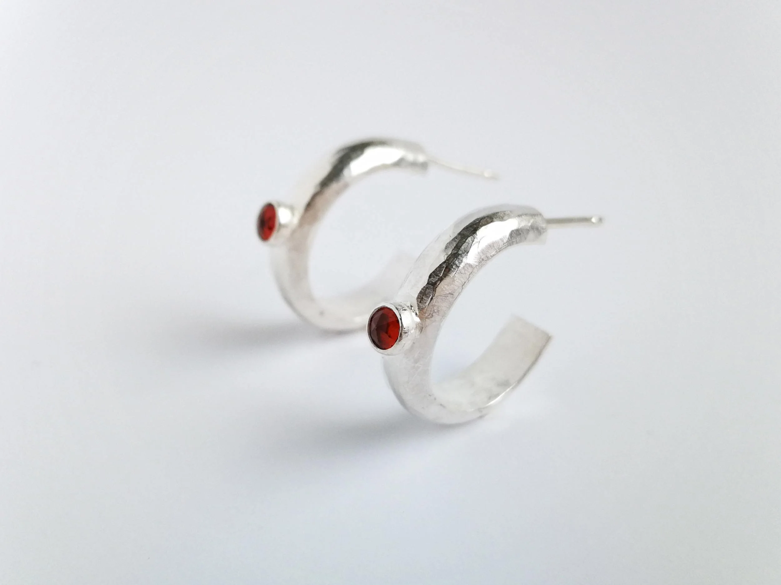 Handmade silver and garnet hoop earrings on white background