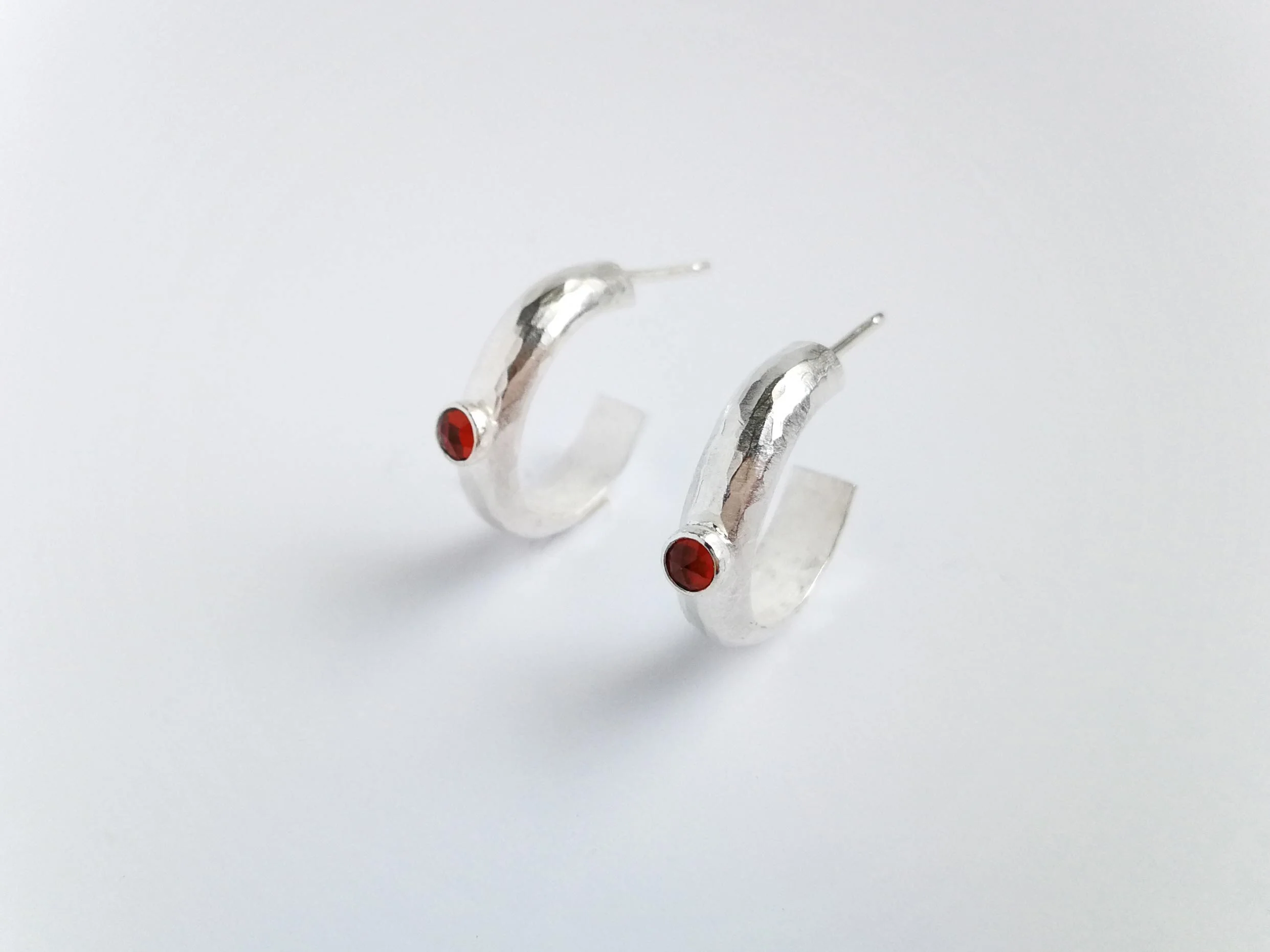 Chunky hoop earrings with red garnet on white background