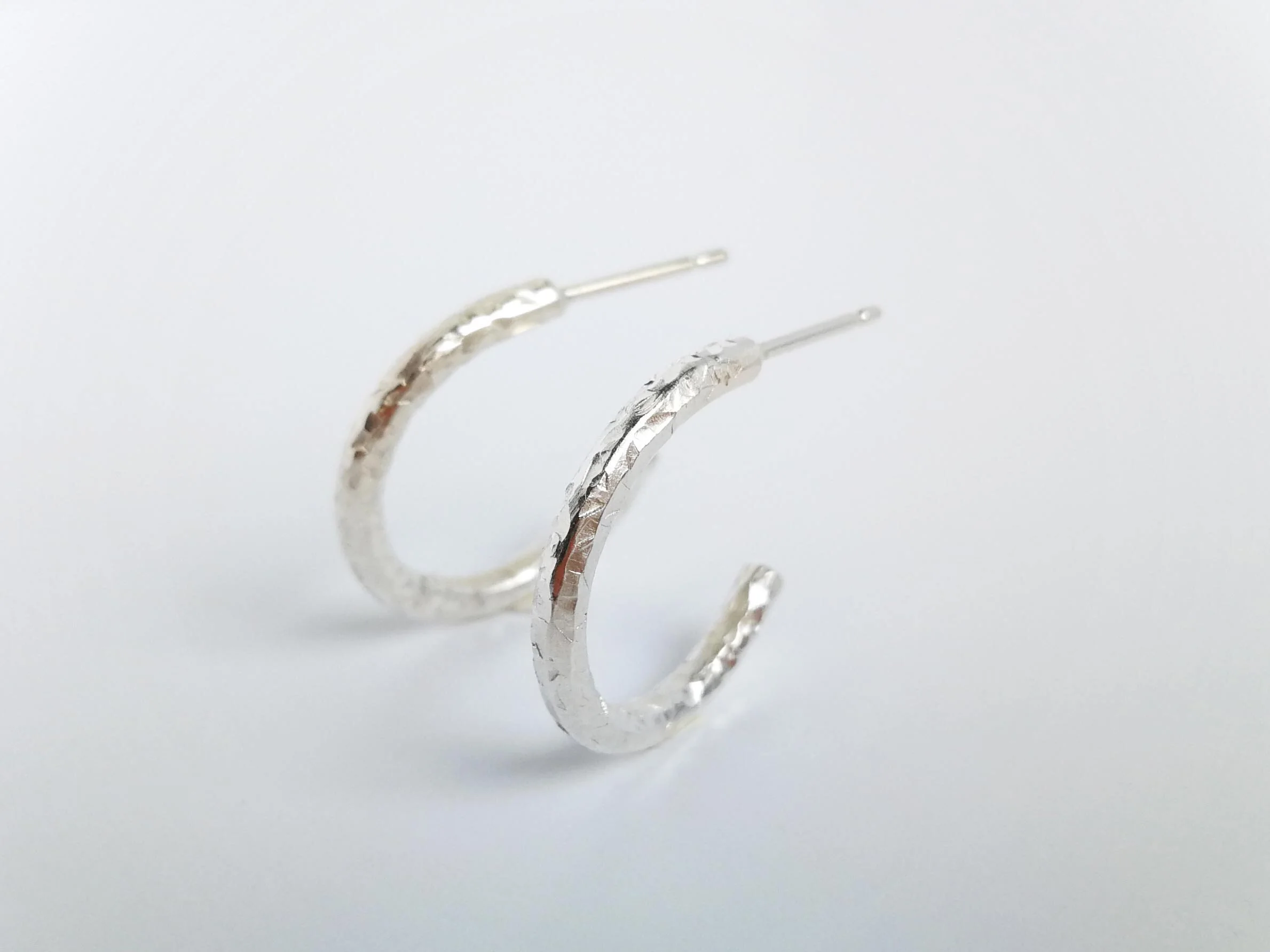 Shiny recycled silver textured hoops on white background