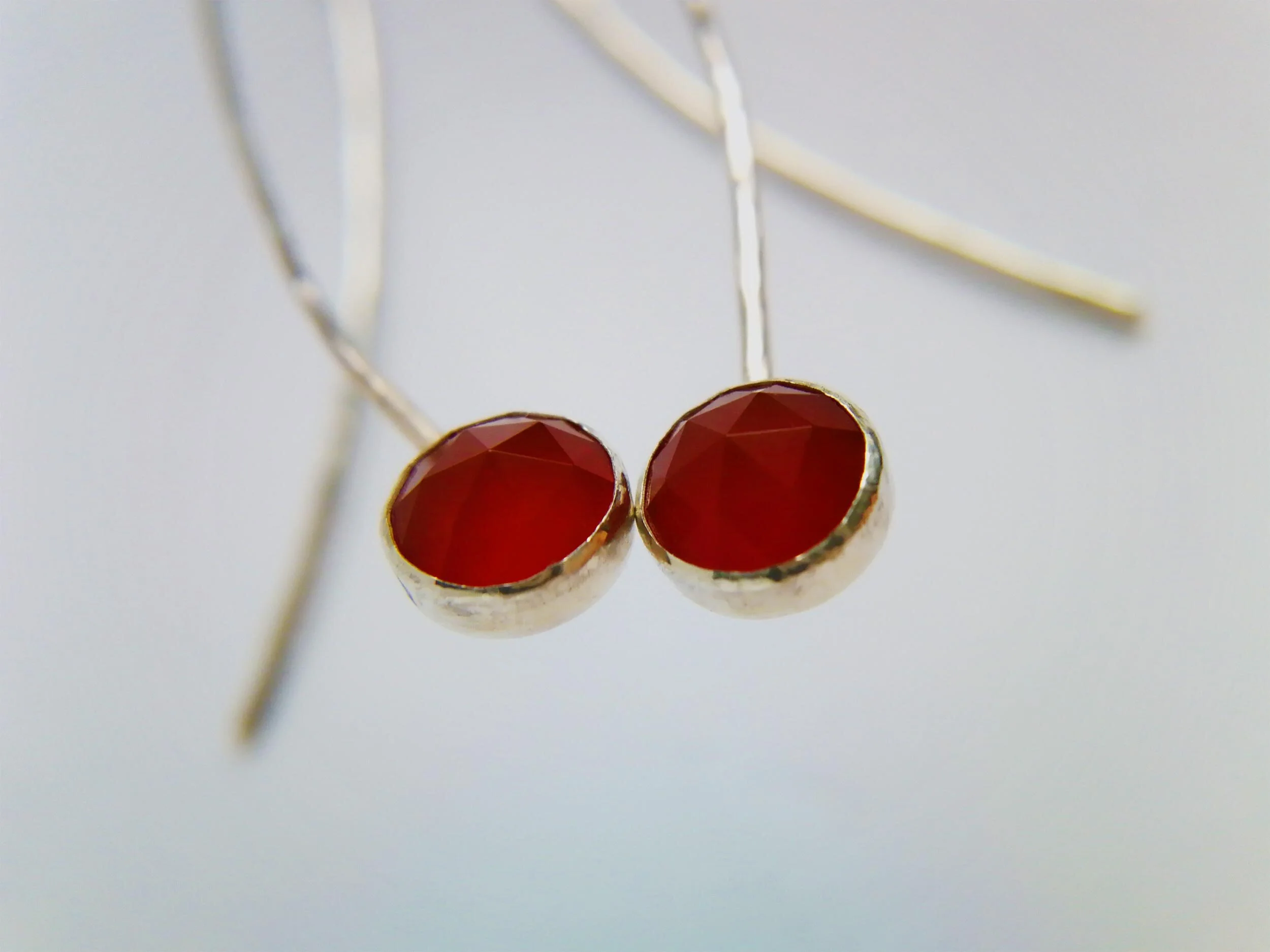 Red faceted carnelian gemstone bezel set earrings on white background