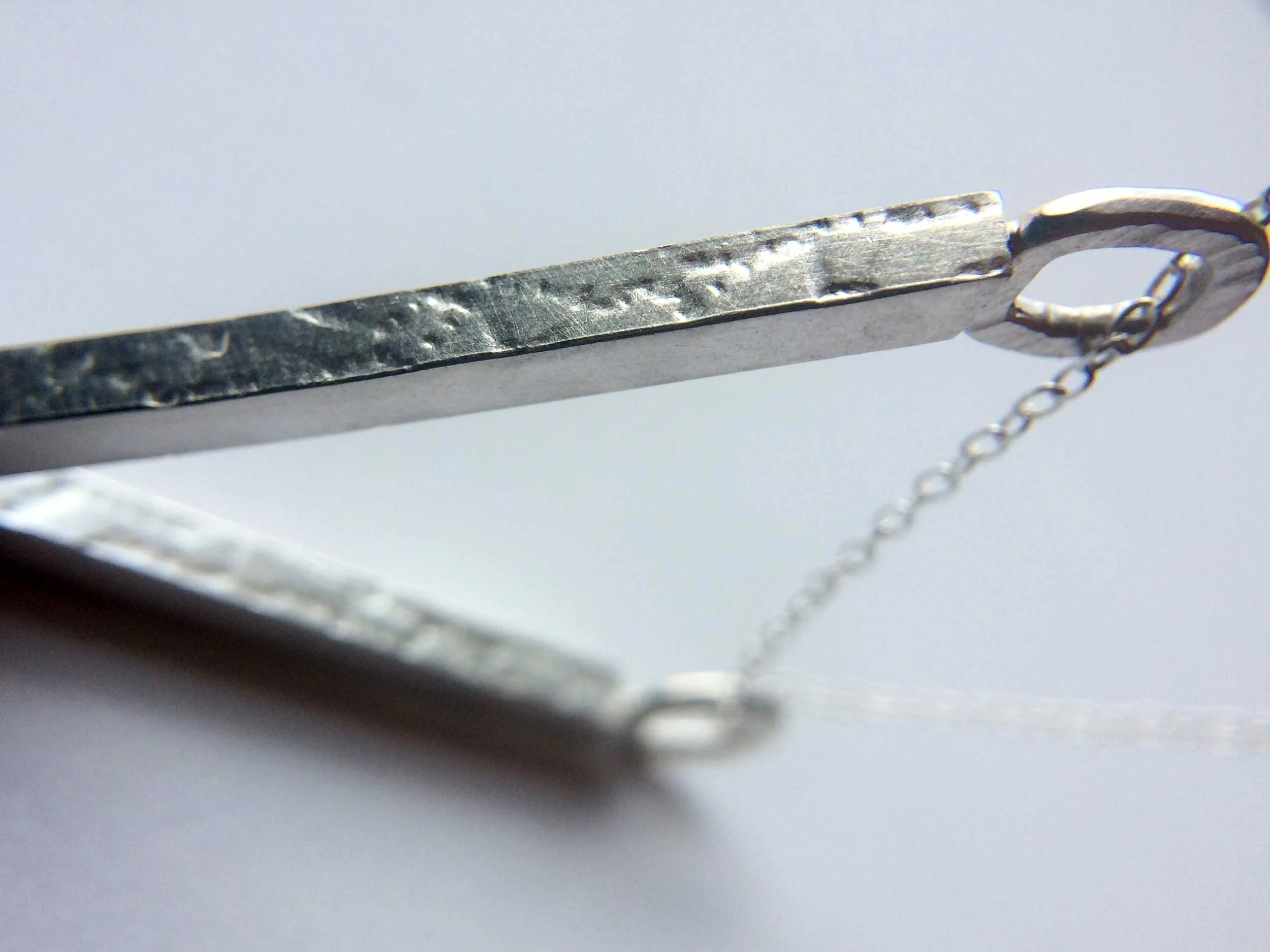 close up textured silver necklace white background