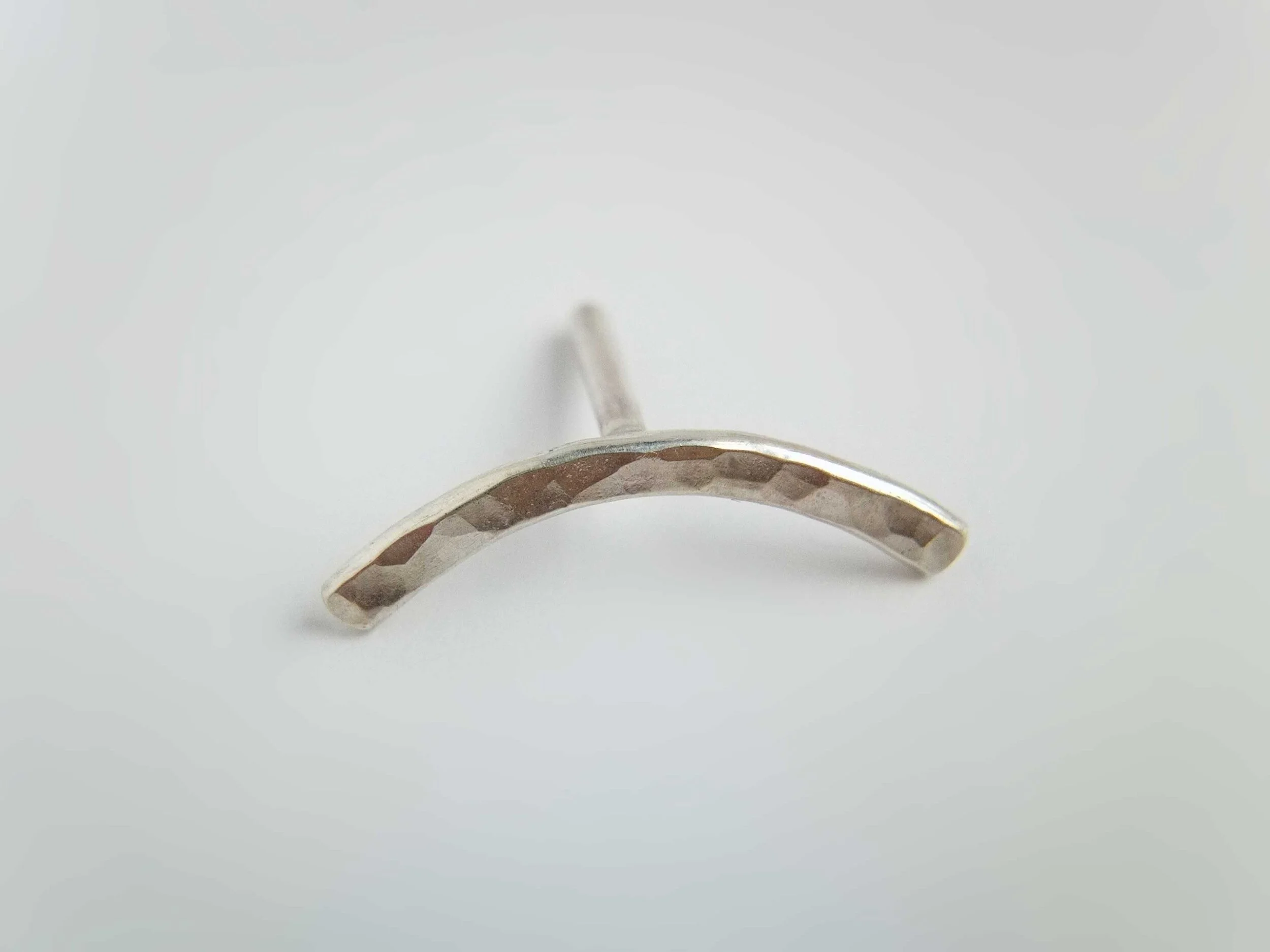 minimalist conch earring hammered from recycled silver on white background