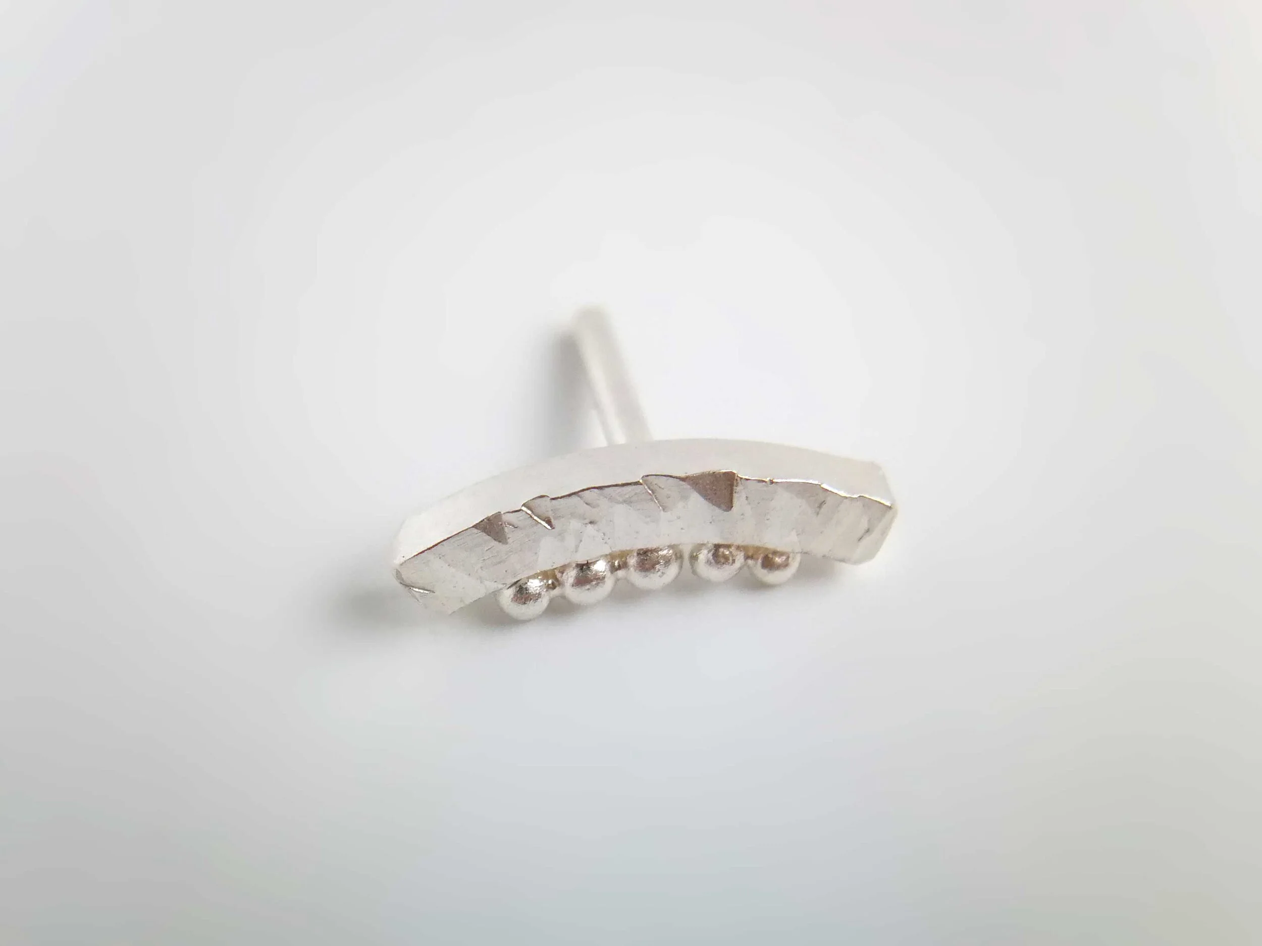 handcrafted recycled silver conch stud on white background victoria grace silversmith