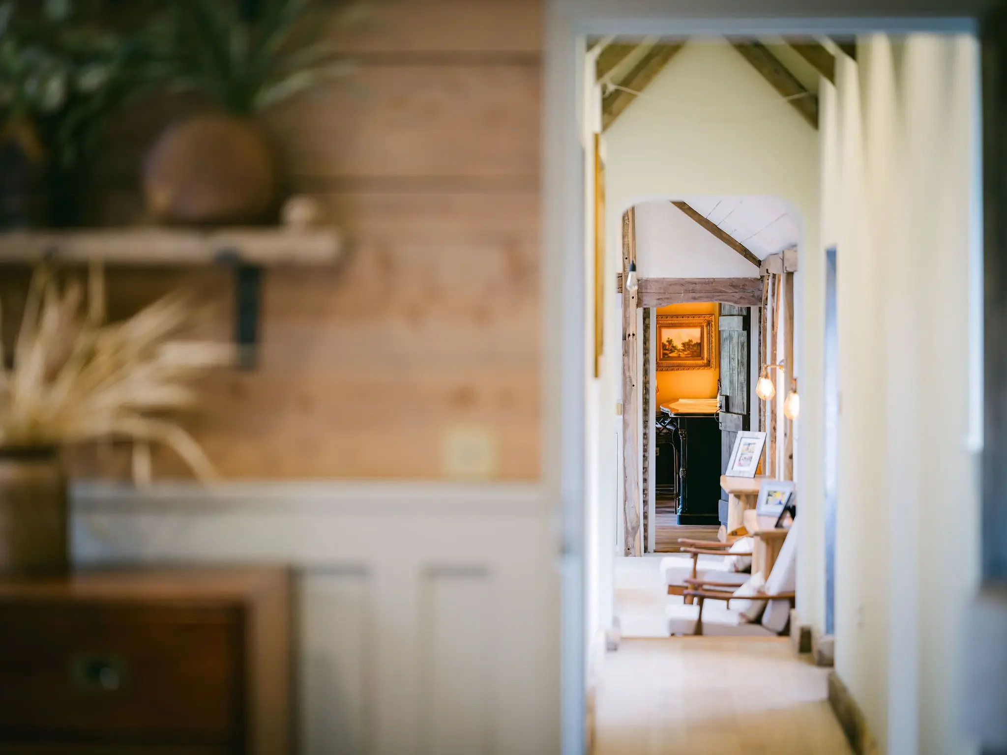 View of a hallway inside a house with multiple wooden archways leading to different rooms, with furniture and artwork visible in the distance.